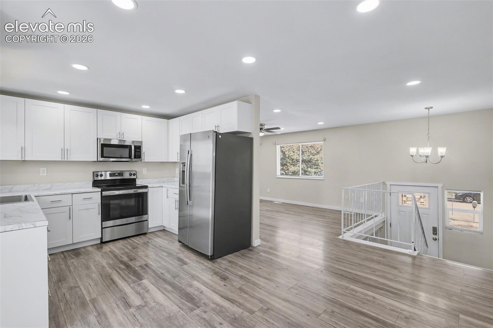 Kitchen featuring white cabinetry, stone-finish countertops, stainless steel appliances, wood-finish flooring, and recessed lighting