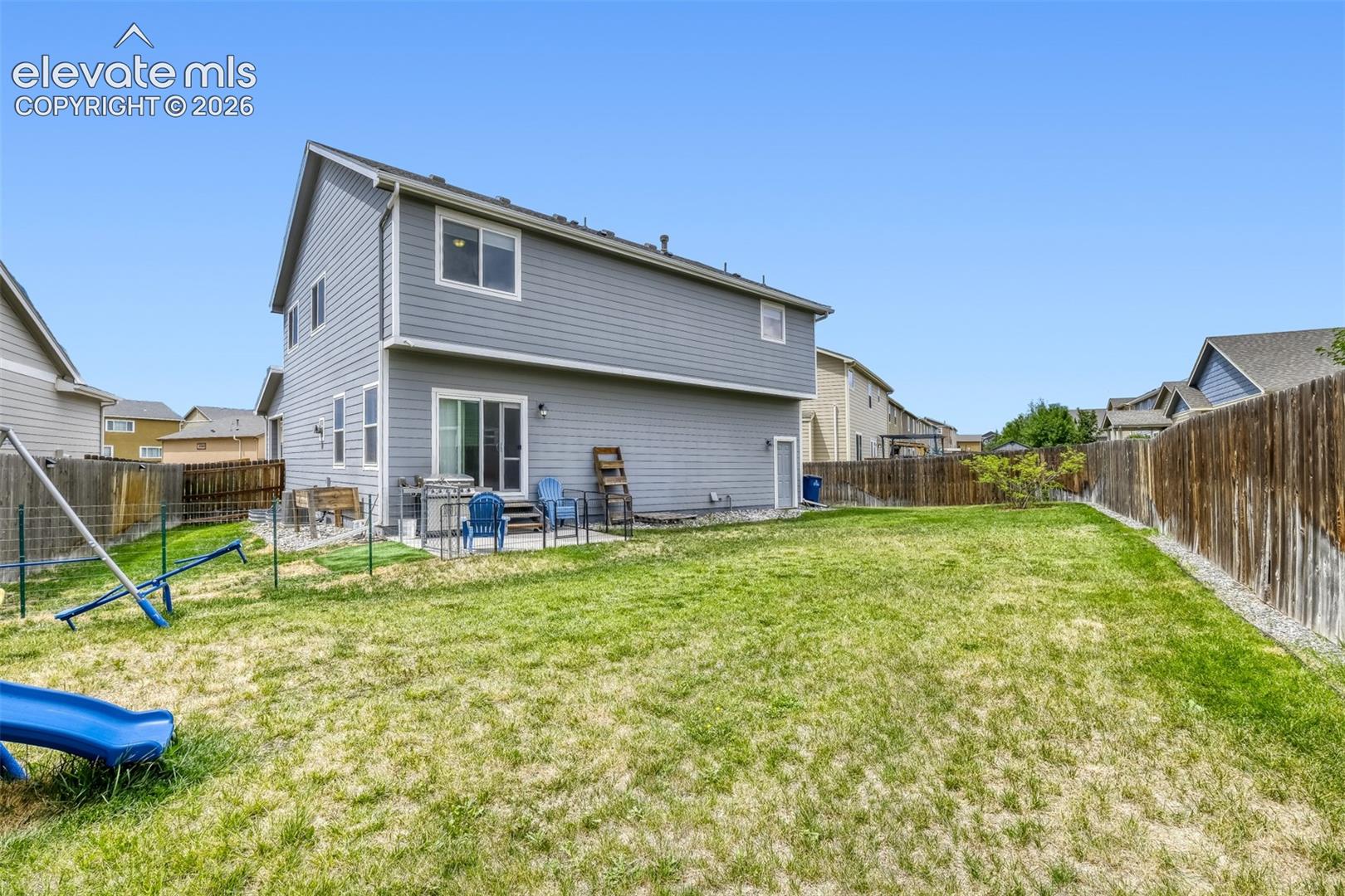 Expansive green lawn with a two-story residence featuring grey siding
