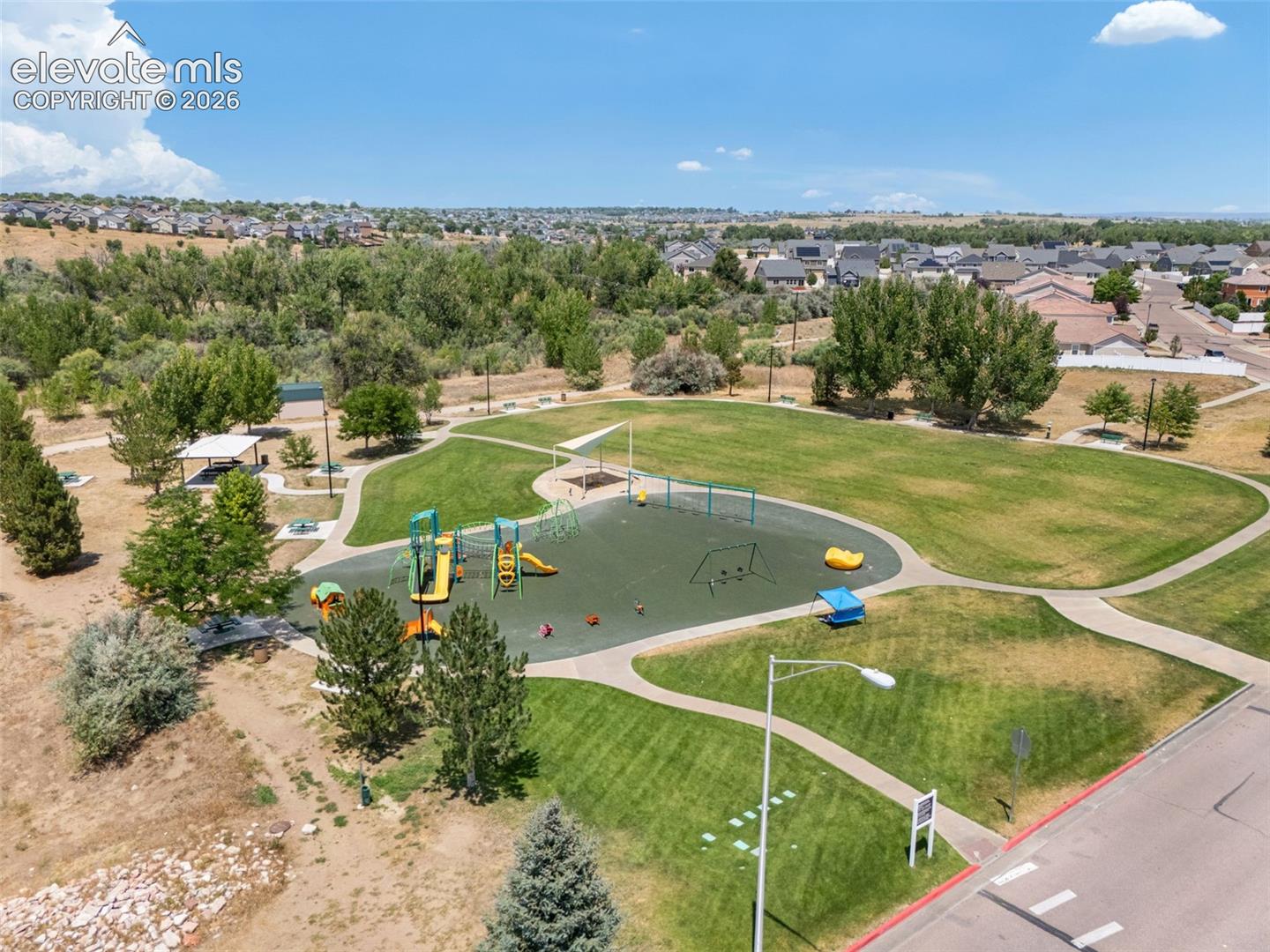 Community green space featuring a playground, paved walking paths, a covered picnic area, and extensive landscaping