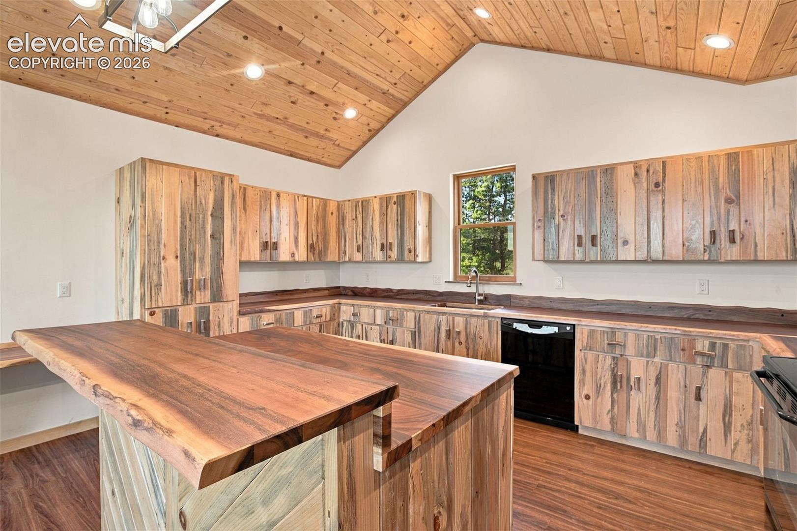 Vaulted wood-plank ceiling, custom natural-edge wood cabinetry, live-edge wood island countertop, recessed lighting, and wood-finish flooring
