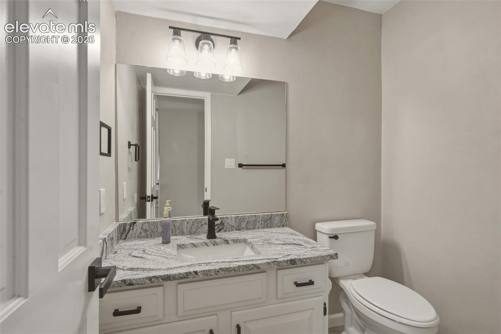 Vanity with stone-finish countertop, undermount sink, and matte black faucet