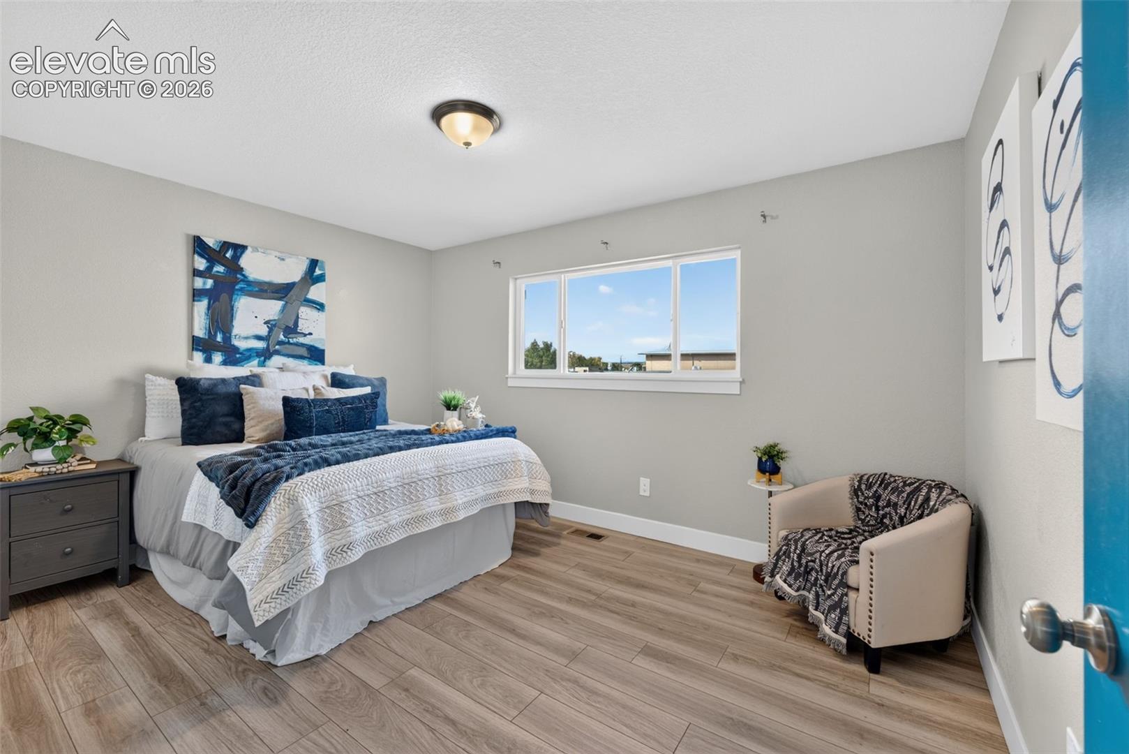 Neutral-toned walls, wood-finish flooring, and a sliding window with clean-lined trim, complemented by a dome-style flush-mount ceiling fixture