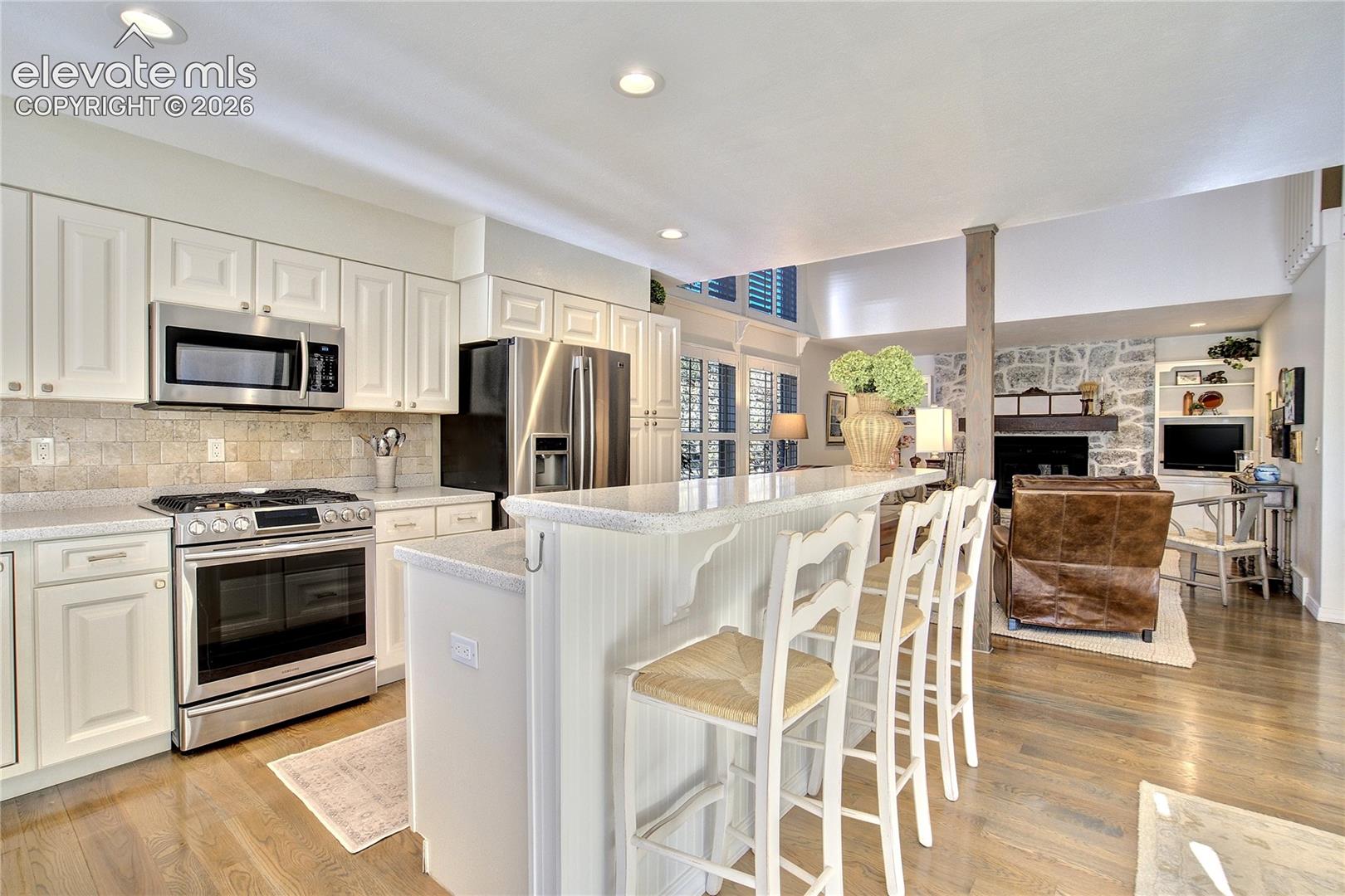 Granite countertops, stainless appliances + a generous island with breakfast seating anchor the light-filled kitchen.