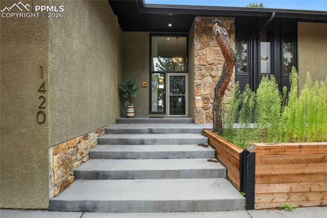 Doorway to property with stone siding and stucco siding