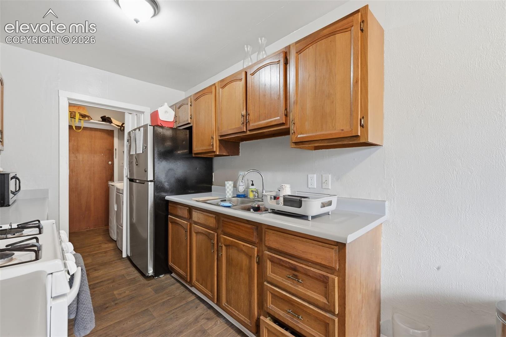 Kitchen featuring wood-finish cabinetry, light-toned countertops, and wood-finish flooring