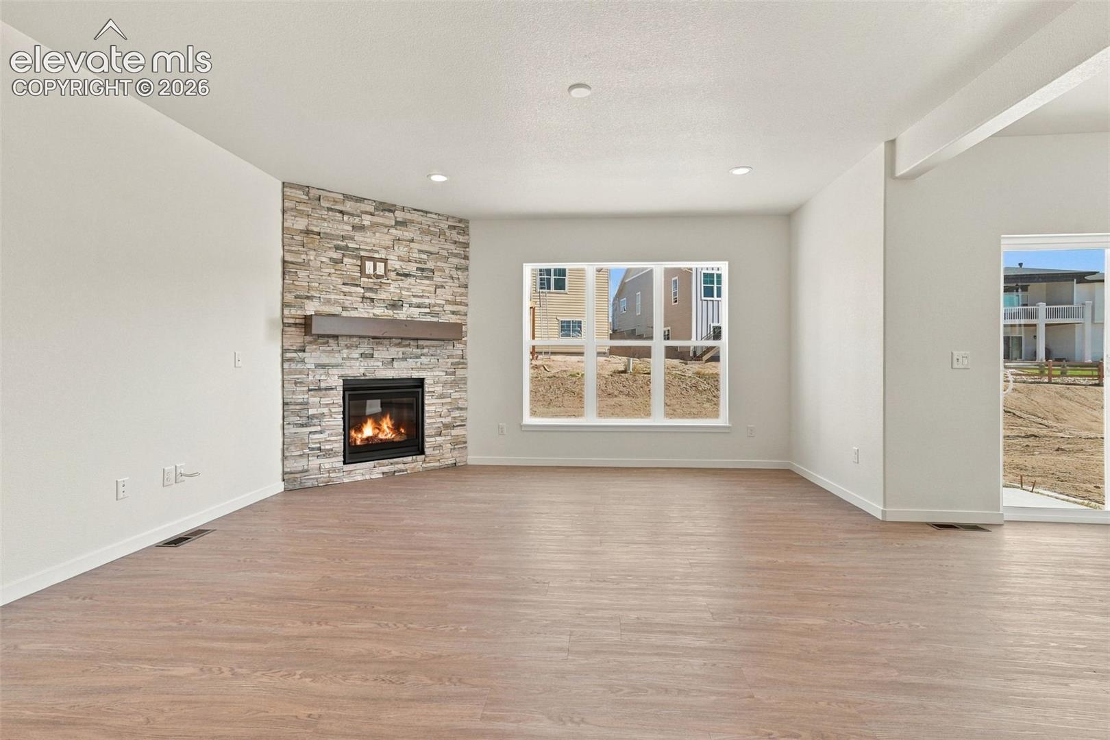 The Great Room features a Gas fireplace with stone extended to the ceiling, wood mantle, LVP Flooring, and recessed lighting.