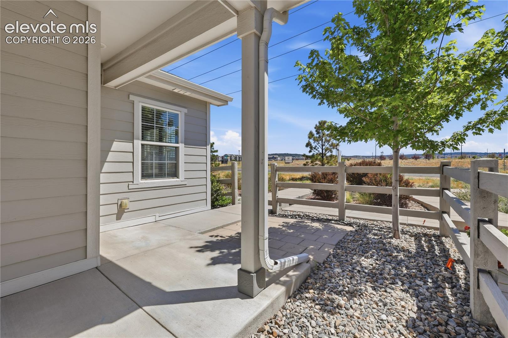Covered concrete patio with horizontal siding and a white-framed window