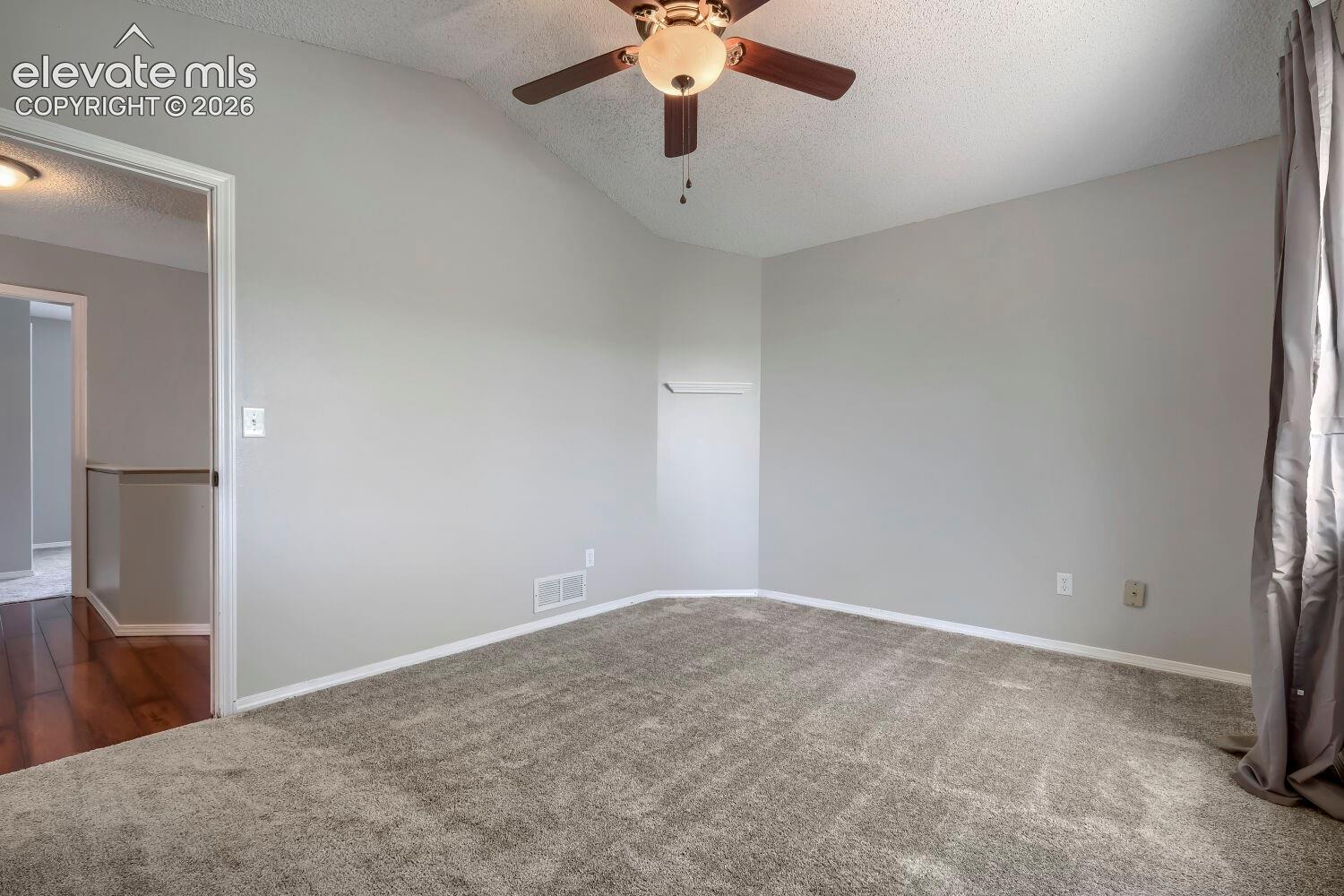 Vaulted ceiling room with ceiling fan light fixture, gray carpet flooring, and neutral wall paint