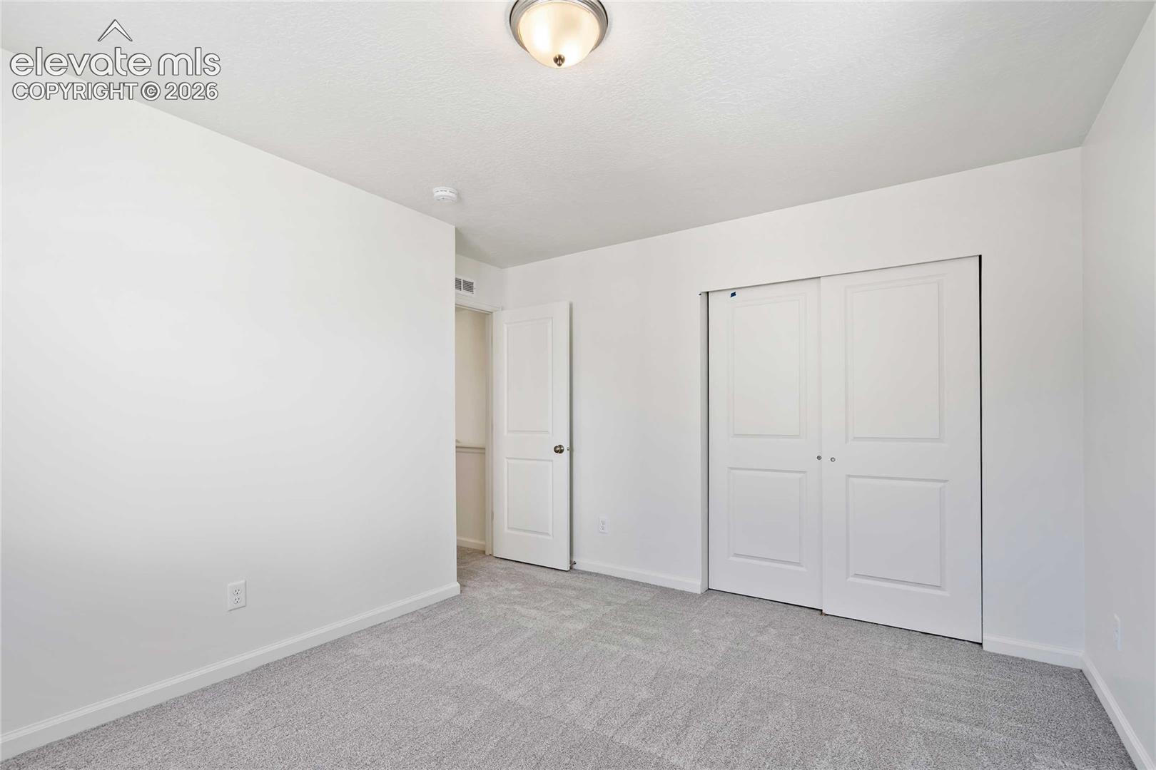 Light gray carpeted flooring, white painted walls, and a ceiling-mounted light fixture
*photos of a model home*