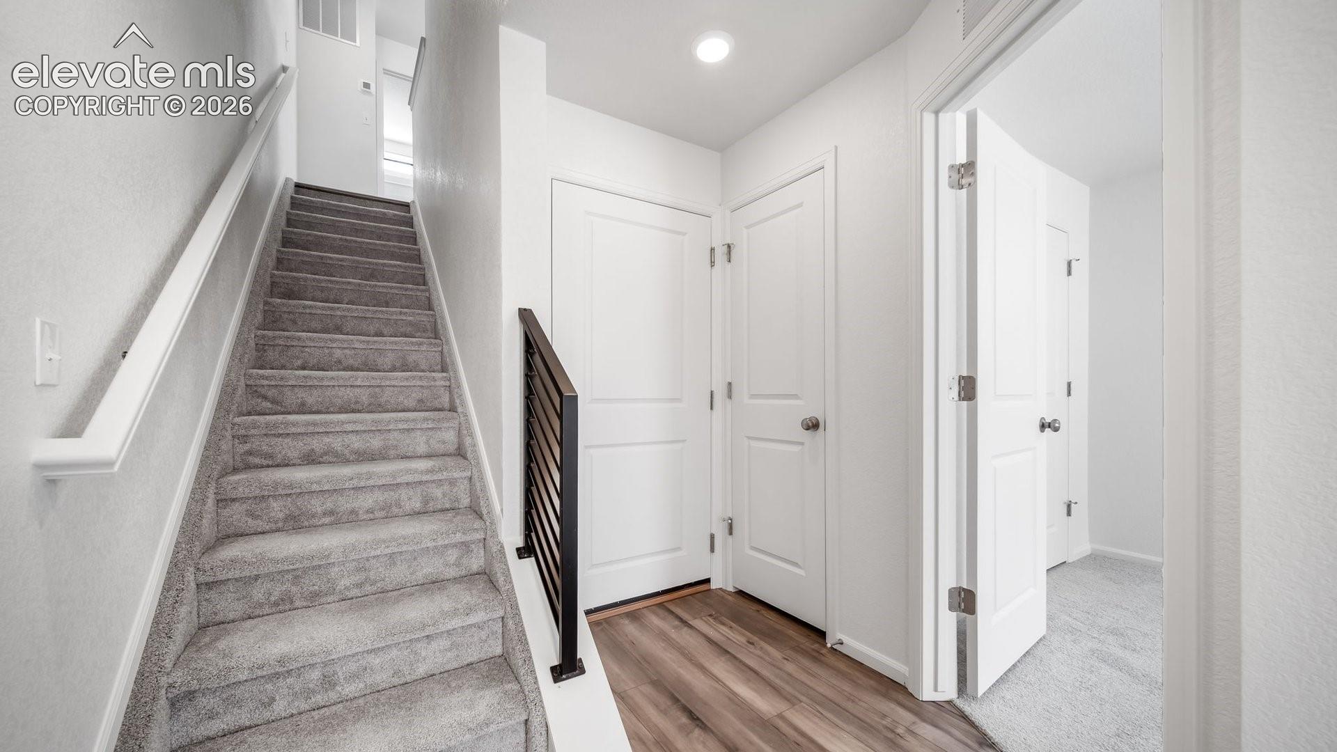Carpeted staircase with white handrail and black metal balusters
*photos of a model home*