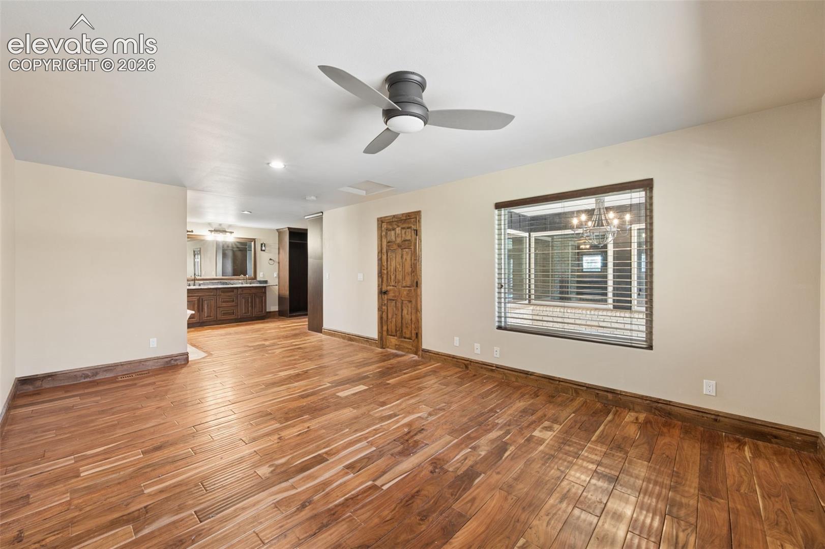 Interior space featuring wood-finish flooring, a three-blade modern ceiling fan, a custom wood-panel door, and an integrated vanity with wood cabinetry