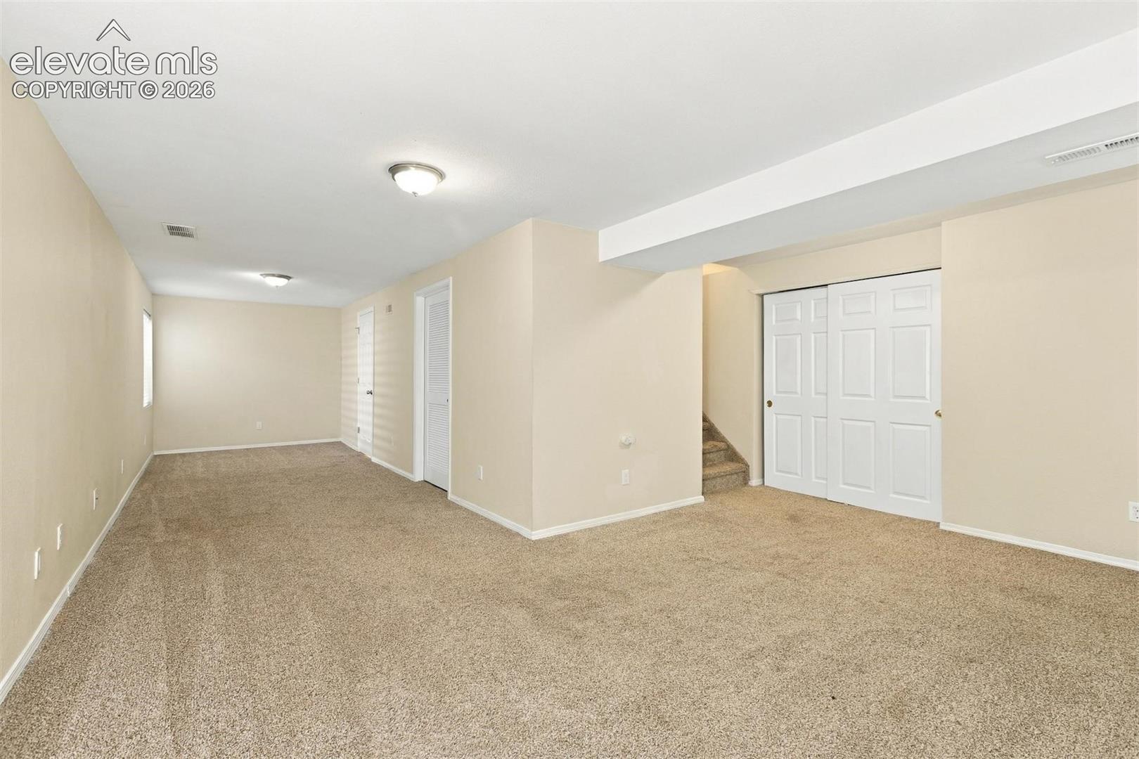 Neutral-toned interior room featuring wall-to-wall carpeting, recessed ceiling lighting, and a white six-panel closet door