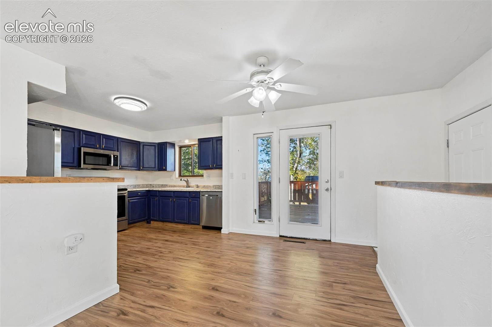 Unstaged kitchen/dining area featuring blue cabinetry, formica countertops, new LVP flooring, and a ceiling fan with integrated lighting