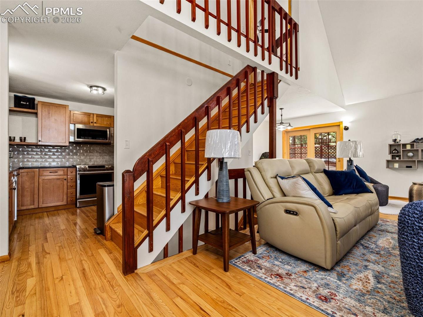 Living area with light wood-style flooring, ceiling fan, and vaulted ceiling