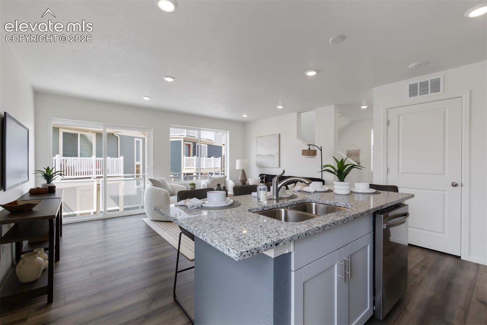 Spacious open-concept living area with wood-finish flooring, recessed lighting, and large sliding glass doors
*photos of a model home*