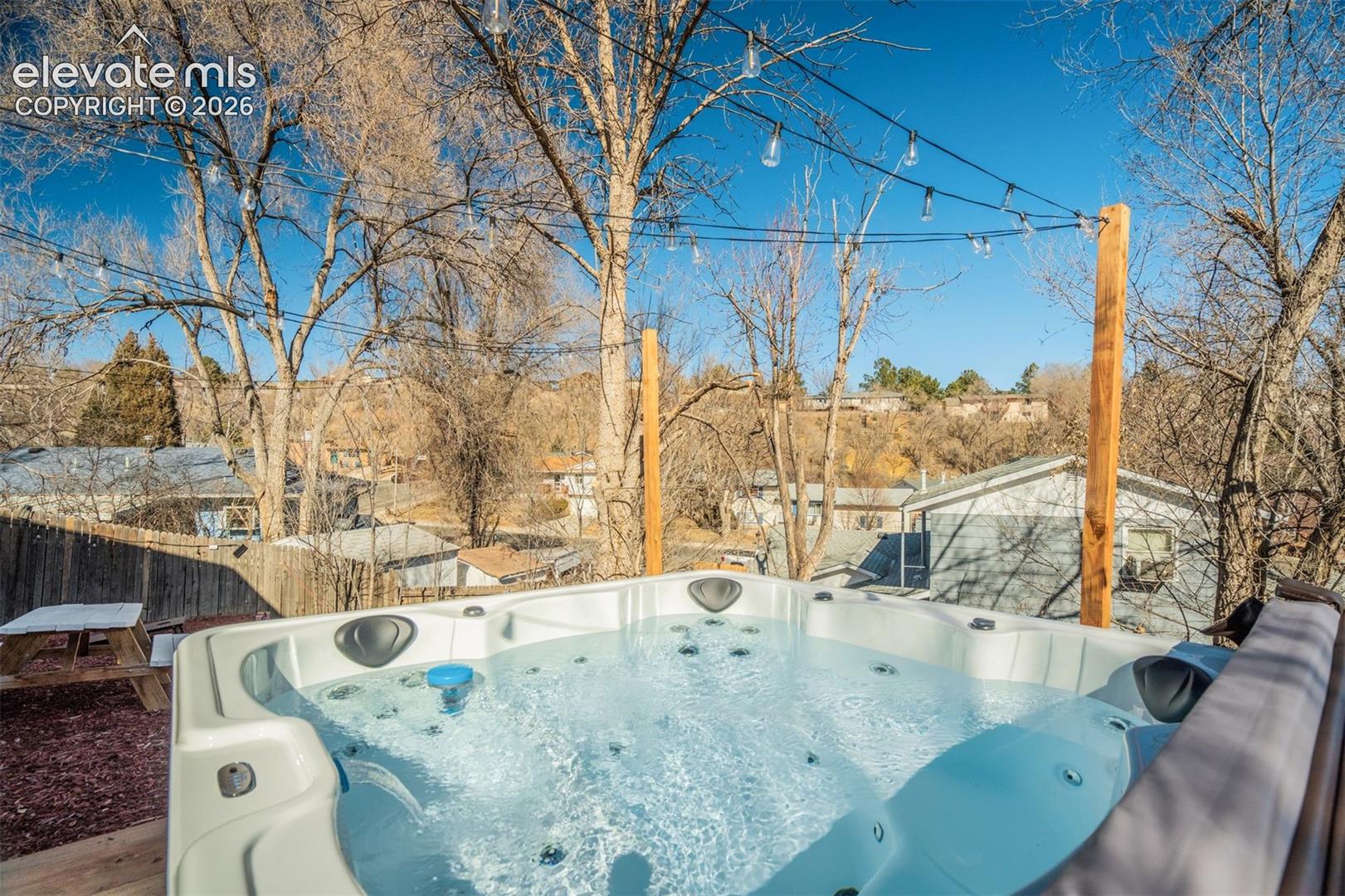 Outdoor spa with a fitted cover, integrated seating, and a string light installation