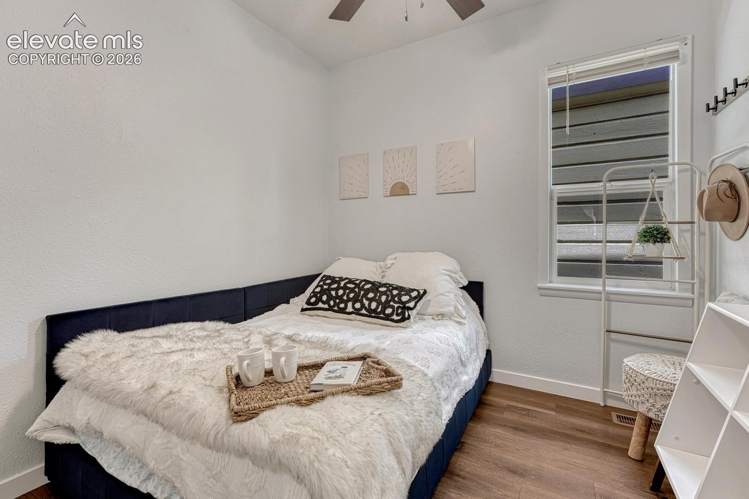 Wood-finish flooring throughout, bright white walls, and a window with blinds