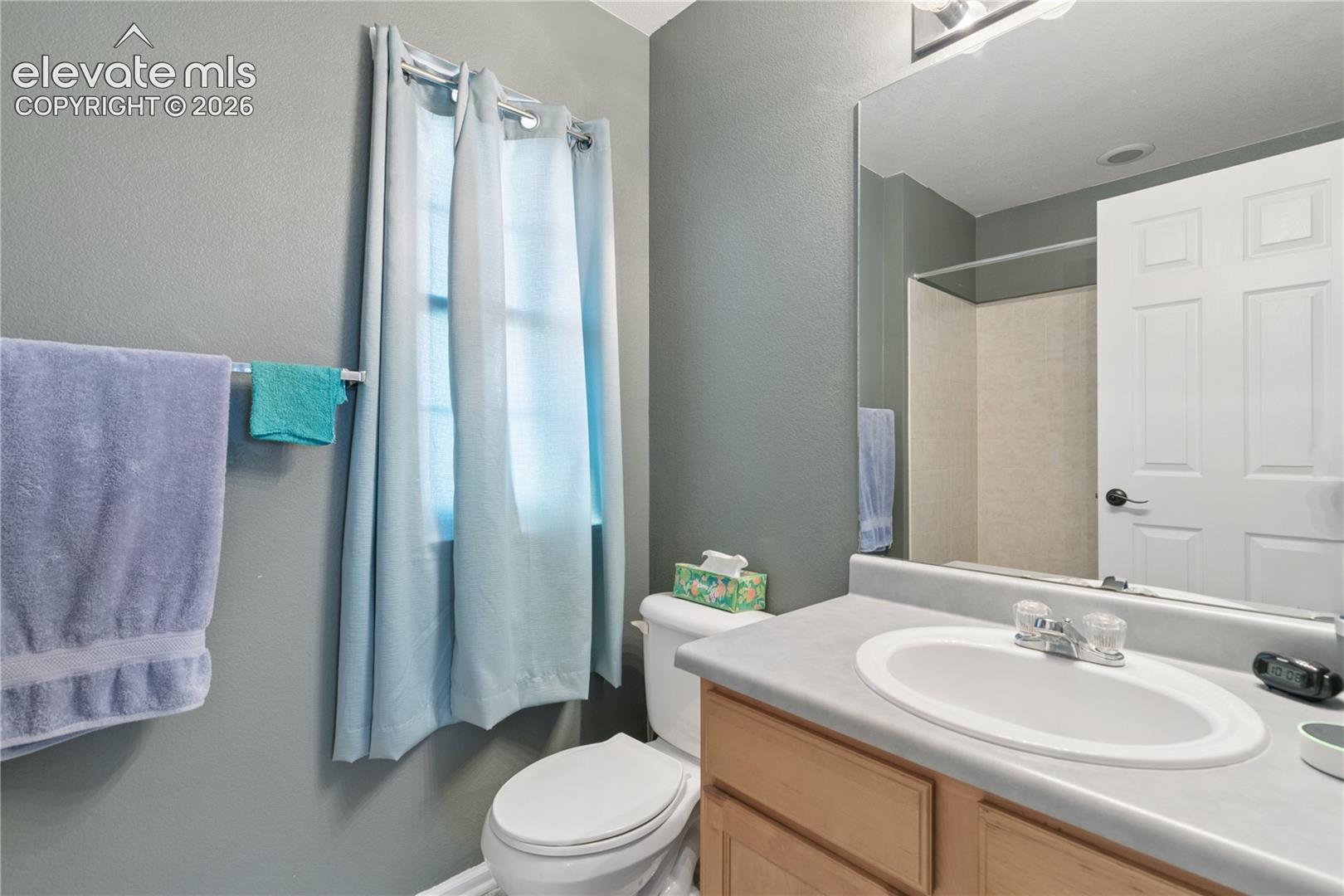 Vanity with an oval sink and chrome faucet, wood-finish cabinetry, and a full-width mirror