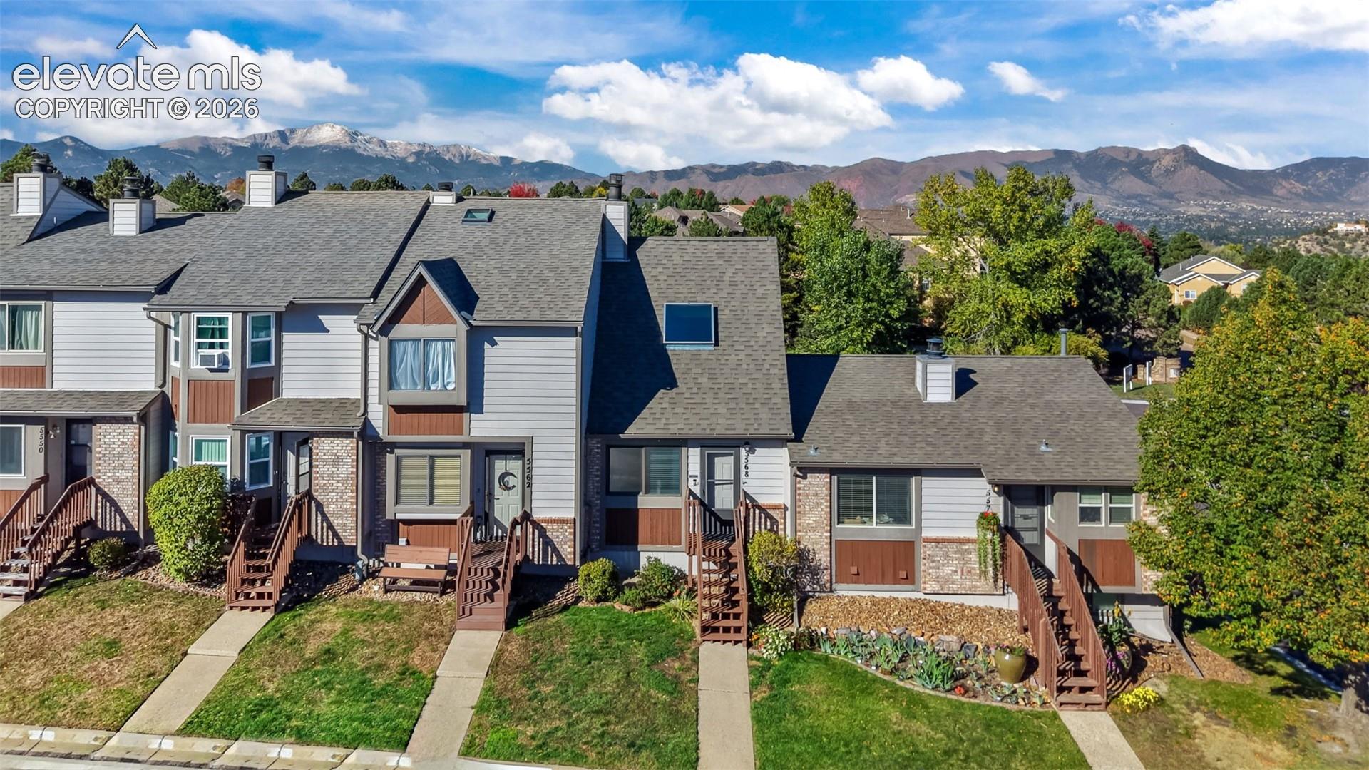 Multi-level exterior featuring wood and stone siding, gabled rooflines, integrated skylights, and mountain scenery