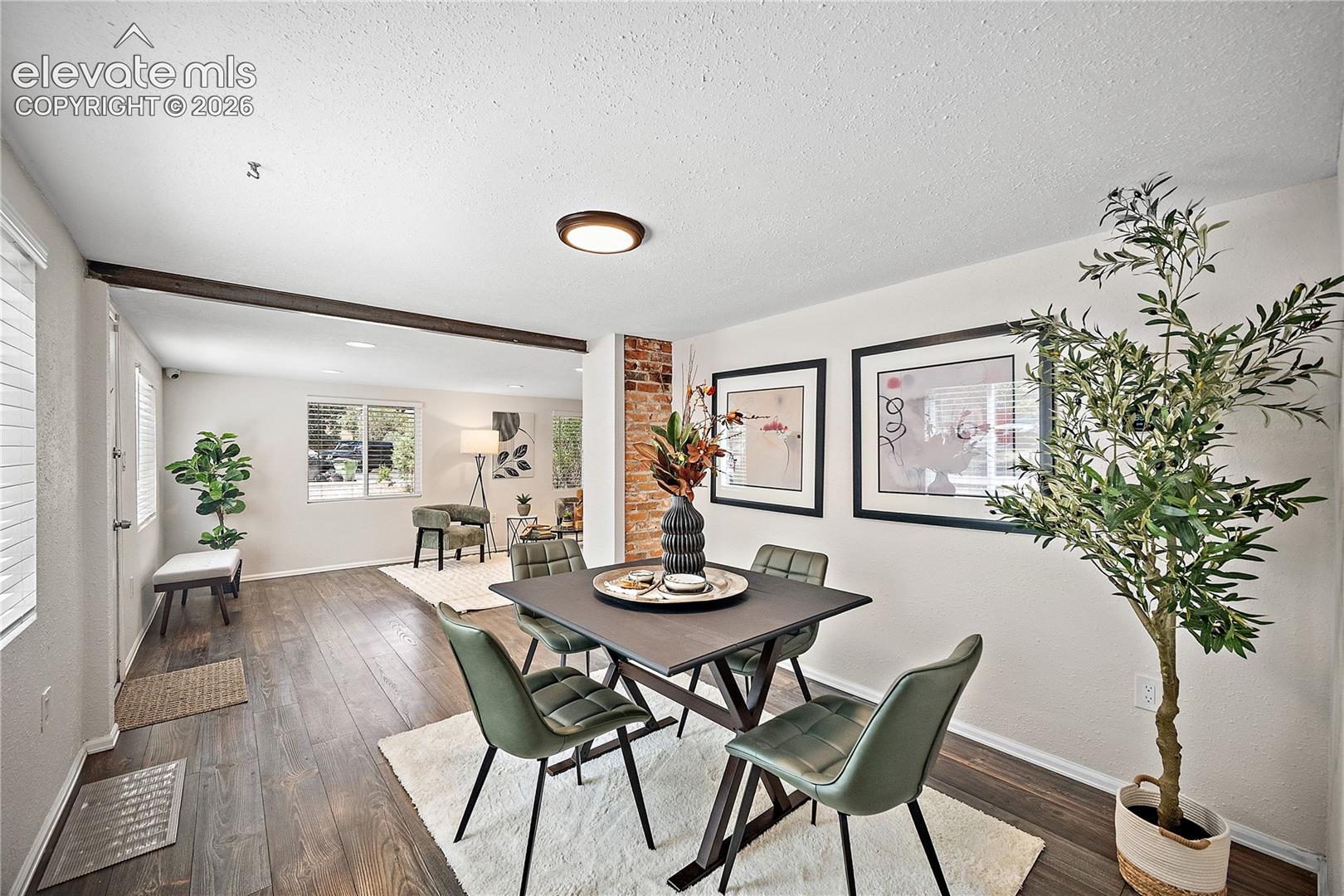 Dining area featuring wood-finish flooring, a partial exposed brick wall, and a recessed ceiling light fixture