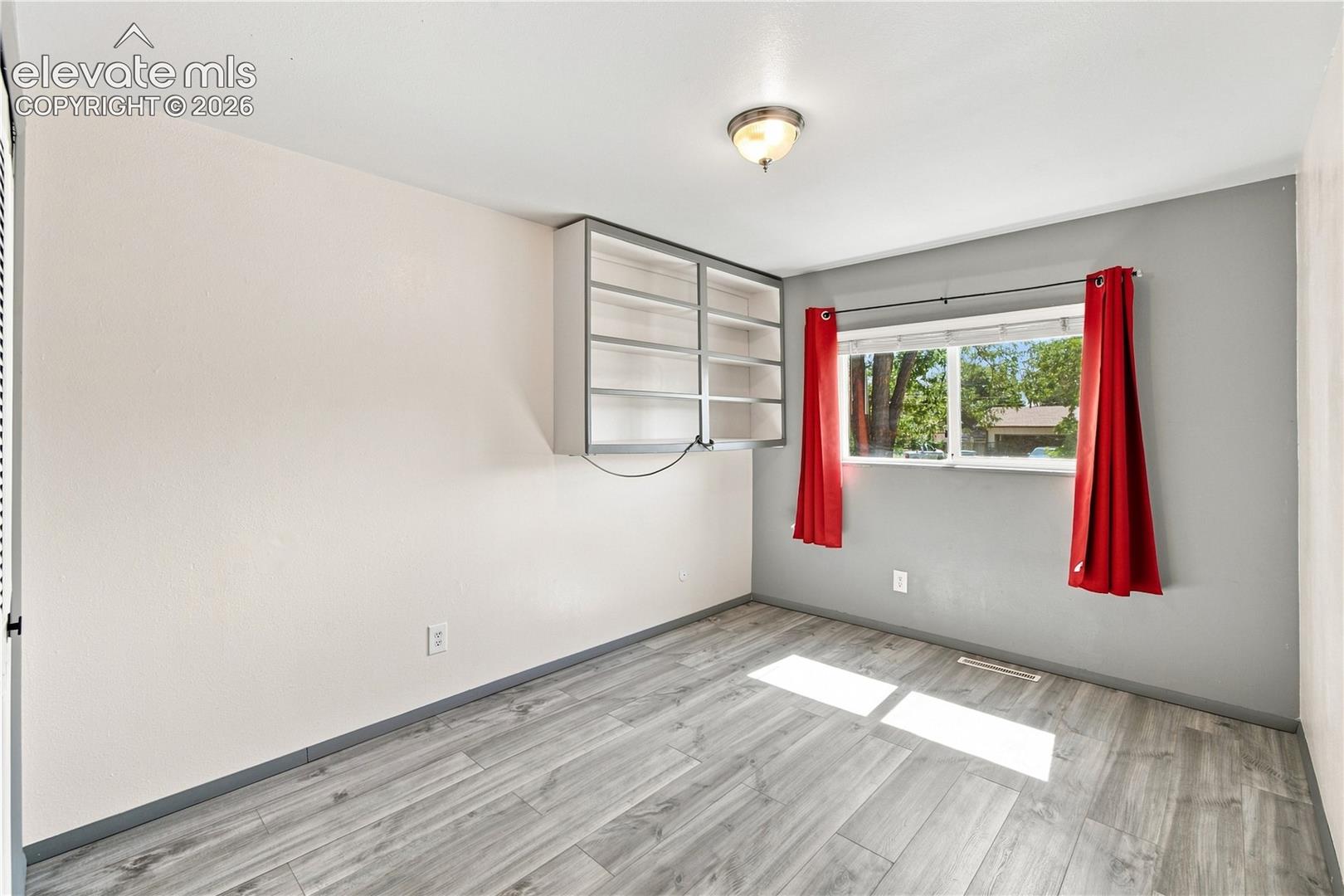 Wood-finish flooring, built-in shelving, and a double-pane window
