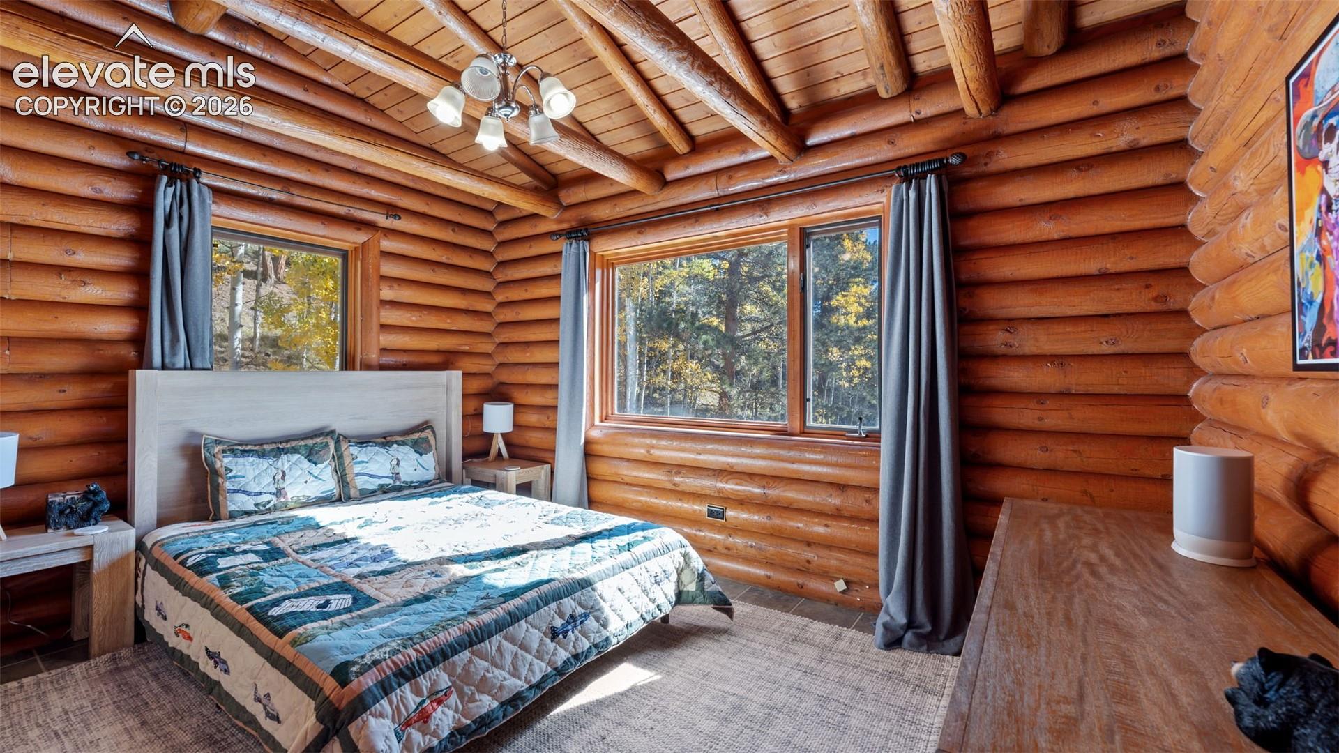 Exposed log walls, vaulted ceiling with exposed timber rafters, and large windows