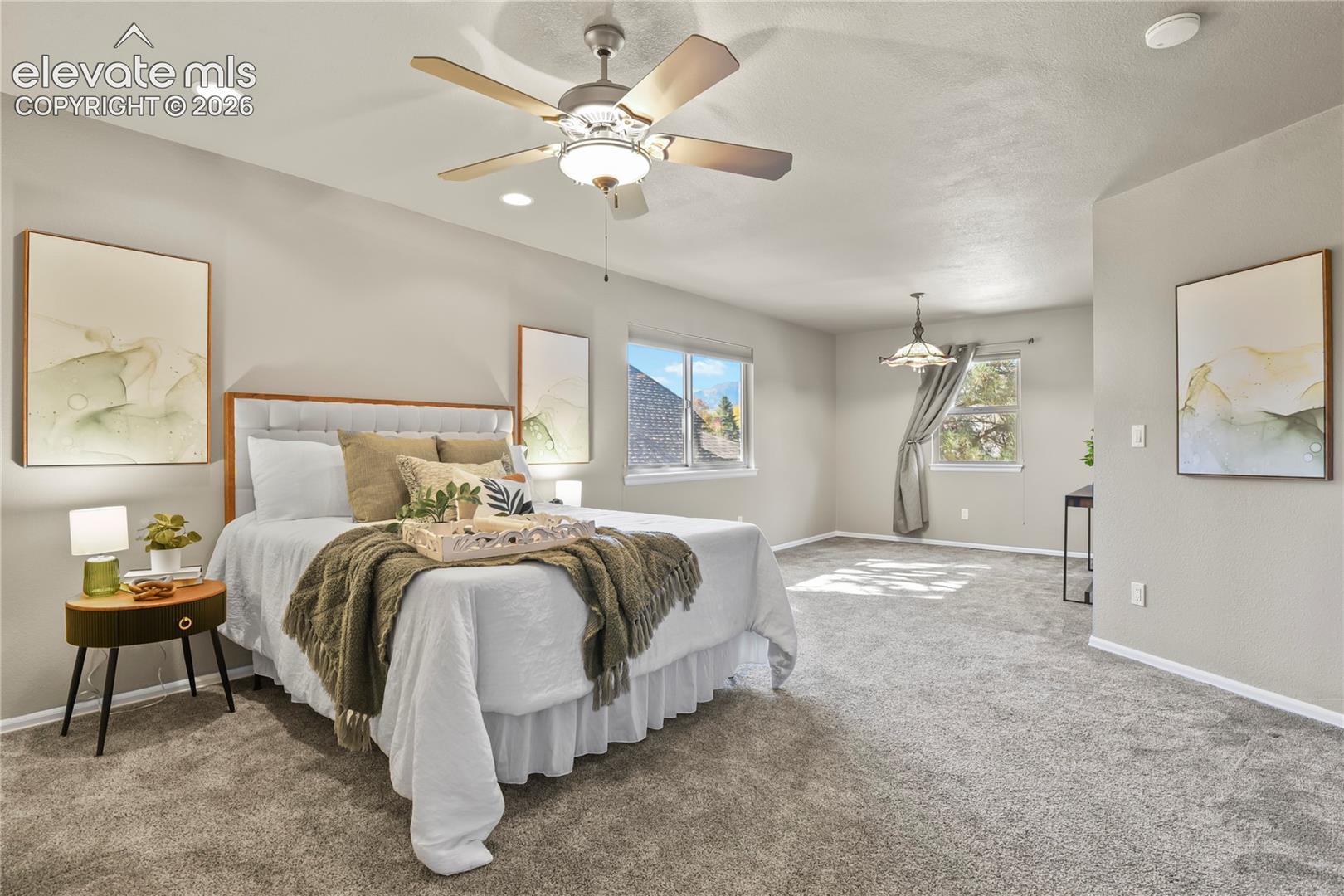 Spacious room featuring large seating area with neutral wall tones, wall-to-wall carpeting, a ceiling fan with integrated lighting, recessed lighting, and multiple windows