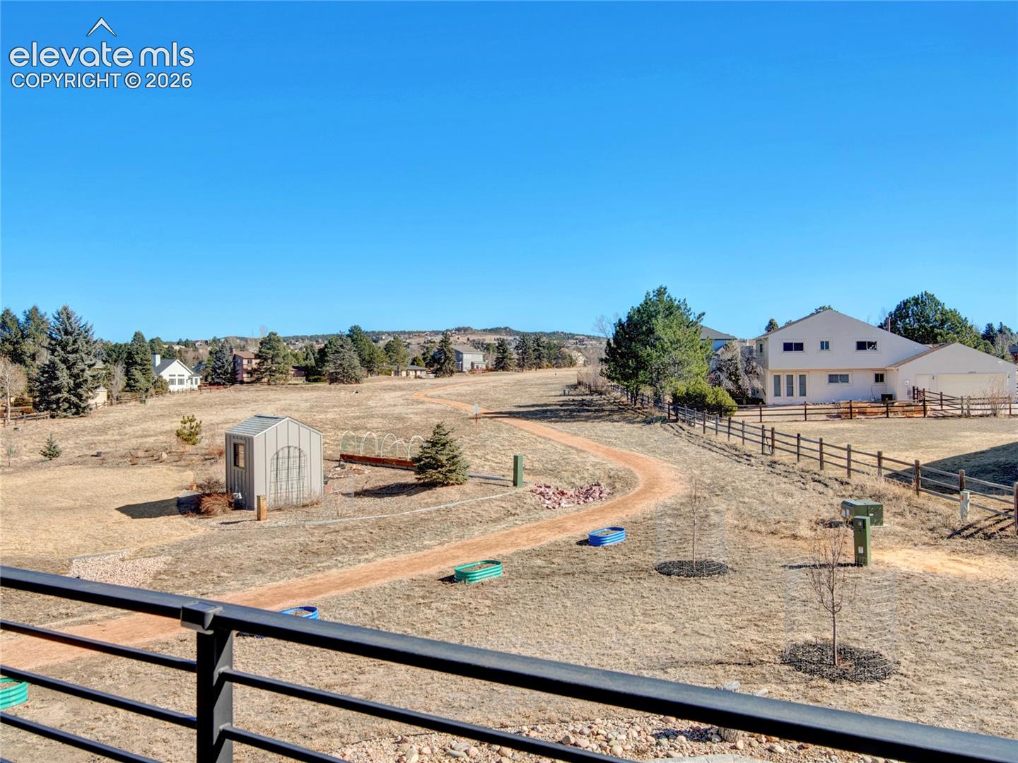 Expansive property featuring a winding dirt path, a small shed, and a wood fence