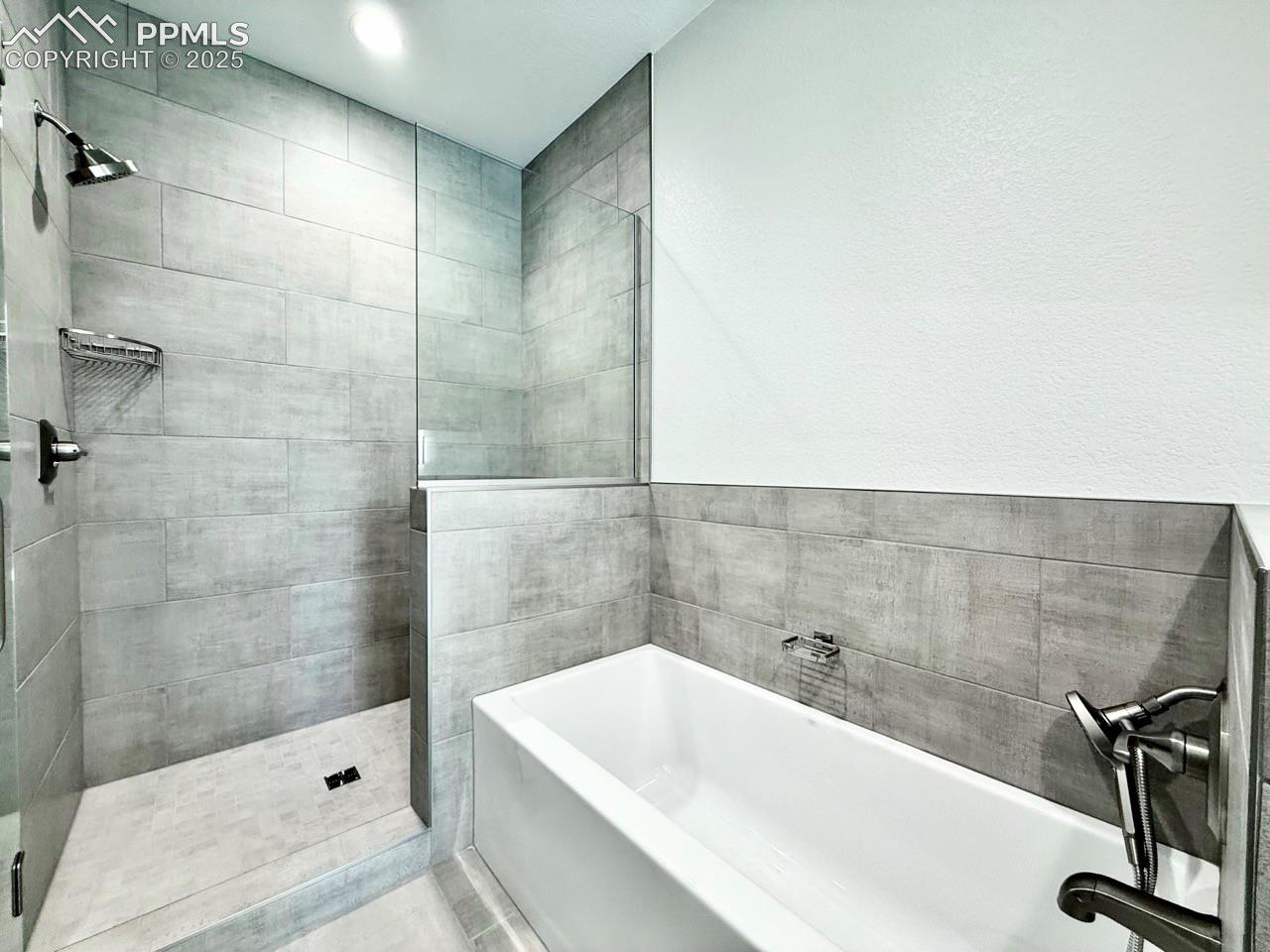 Luxurious Primary Bathroom with Quartz Countertop, Deep Soaking Tub, Tiled Shower with Bench and Glass Door, and a Heated Mirror to avoid Fogging.
