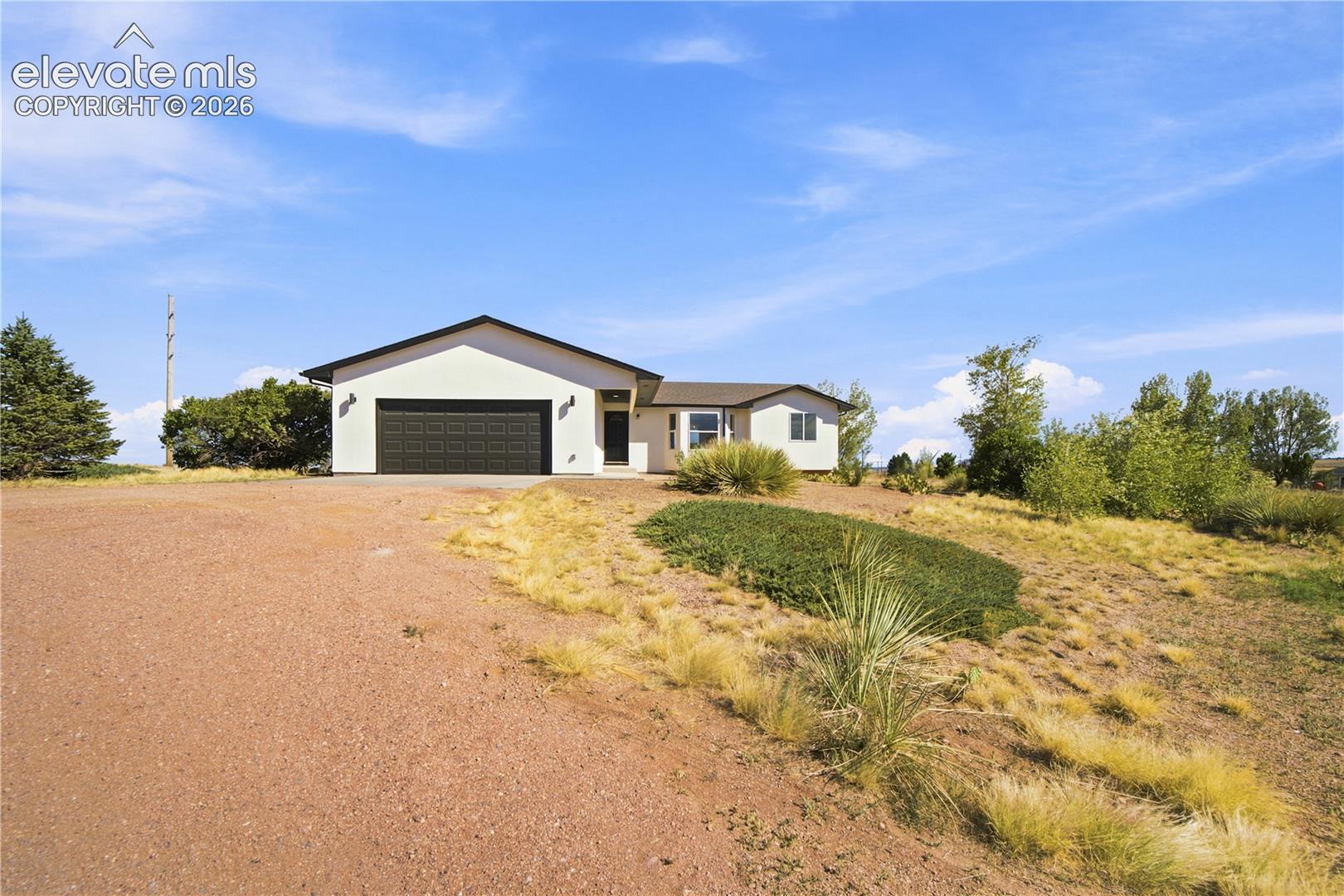 Contemporary stucco exterior with an attached two-car garage, black front door, and a low-sloped roof