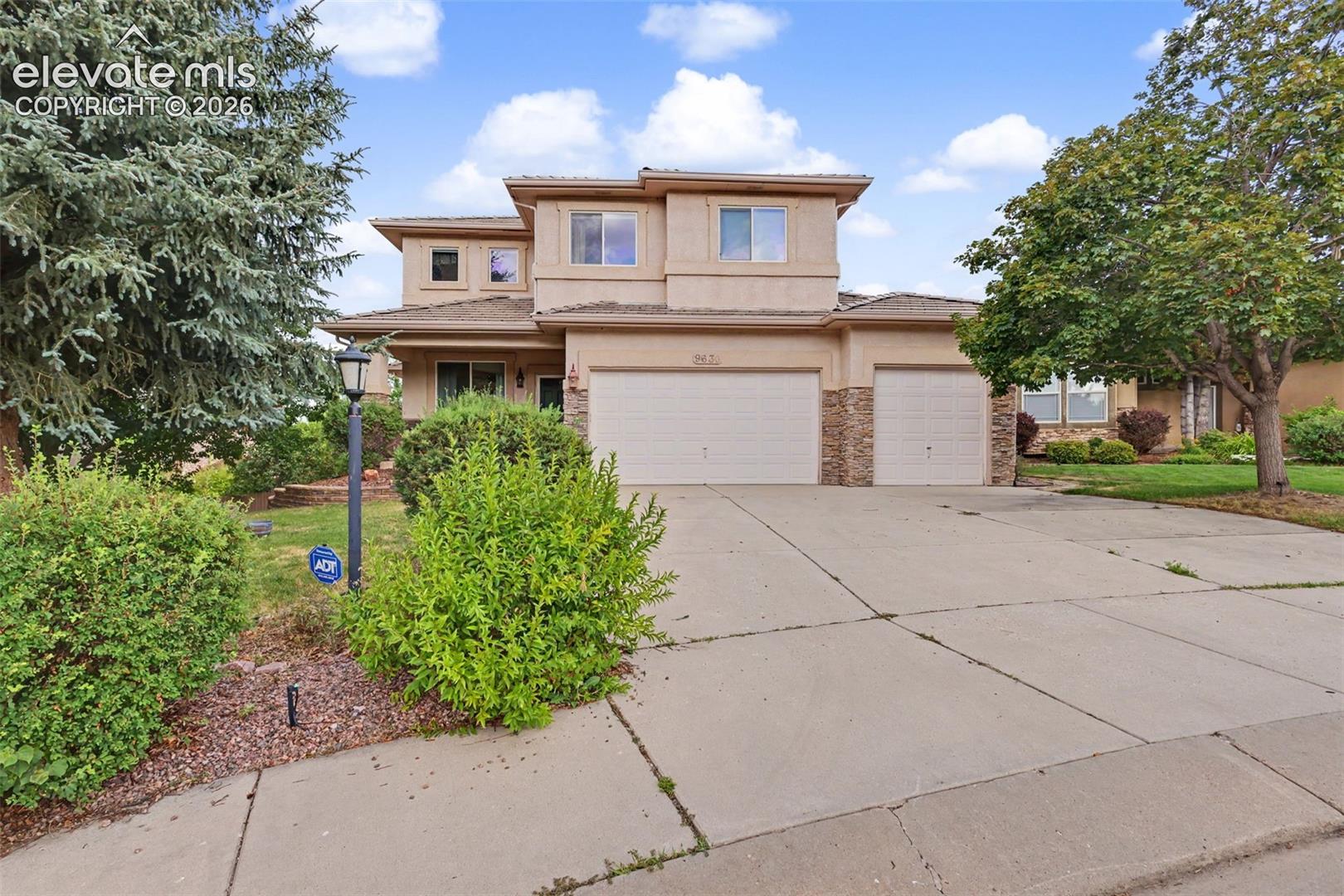Stucco exterior featuring stacked stone accents, two-story construction, and a three-car garage