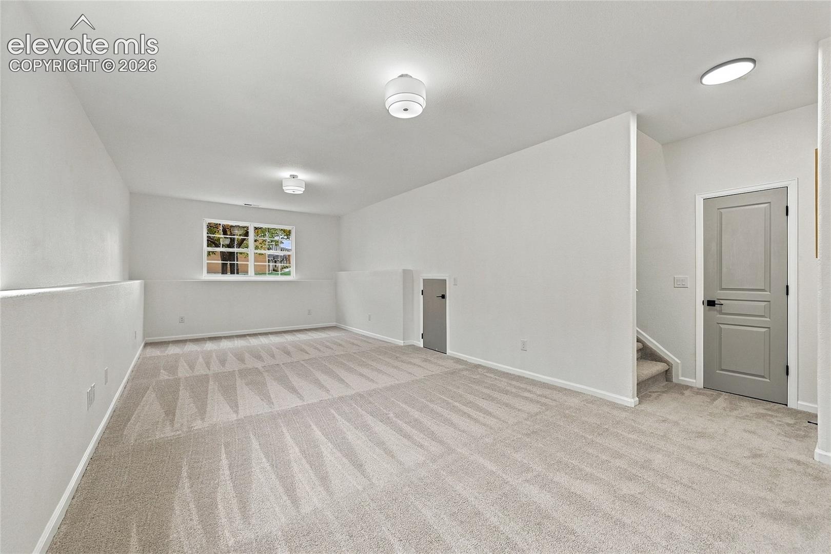 Interior space featuring neutral wall-to-wall carpeting, recessed and semi-flush mount lighting, a multi-pane window, and a paneled interior door with matte black hardware
