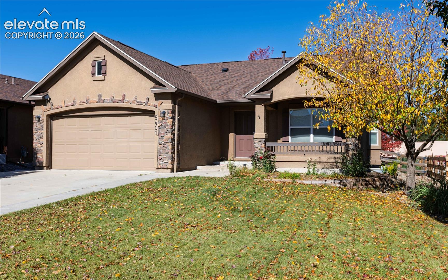 Stucco exterior featuring stacked stone accents, arched garage entrance, covered entryway, and gabled roofline