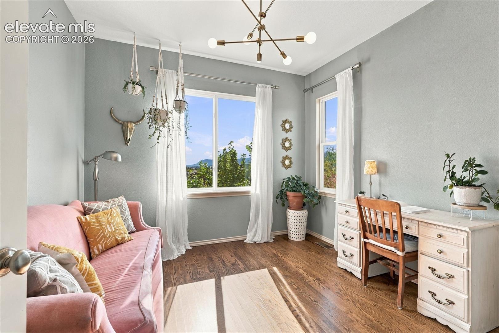 Wood-finish flooring, multi-light modern chandelier, and large dual-pane windows with mountain backdrop