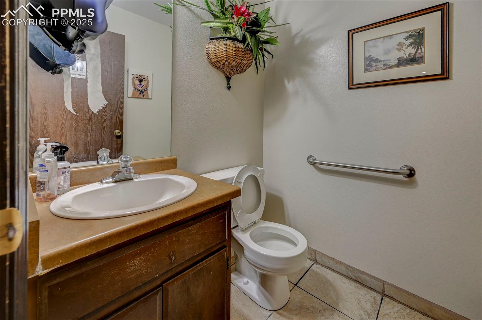Half bath featuring tile patterned floors, vanity, and toilet