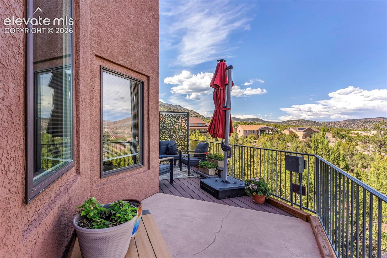 Elevated balcony featuring stucco exterior walls, composite decking, metal railings, and natural mountain scenery