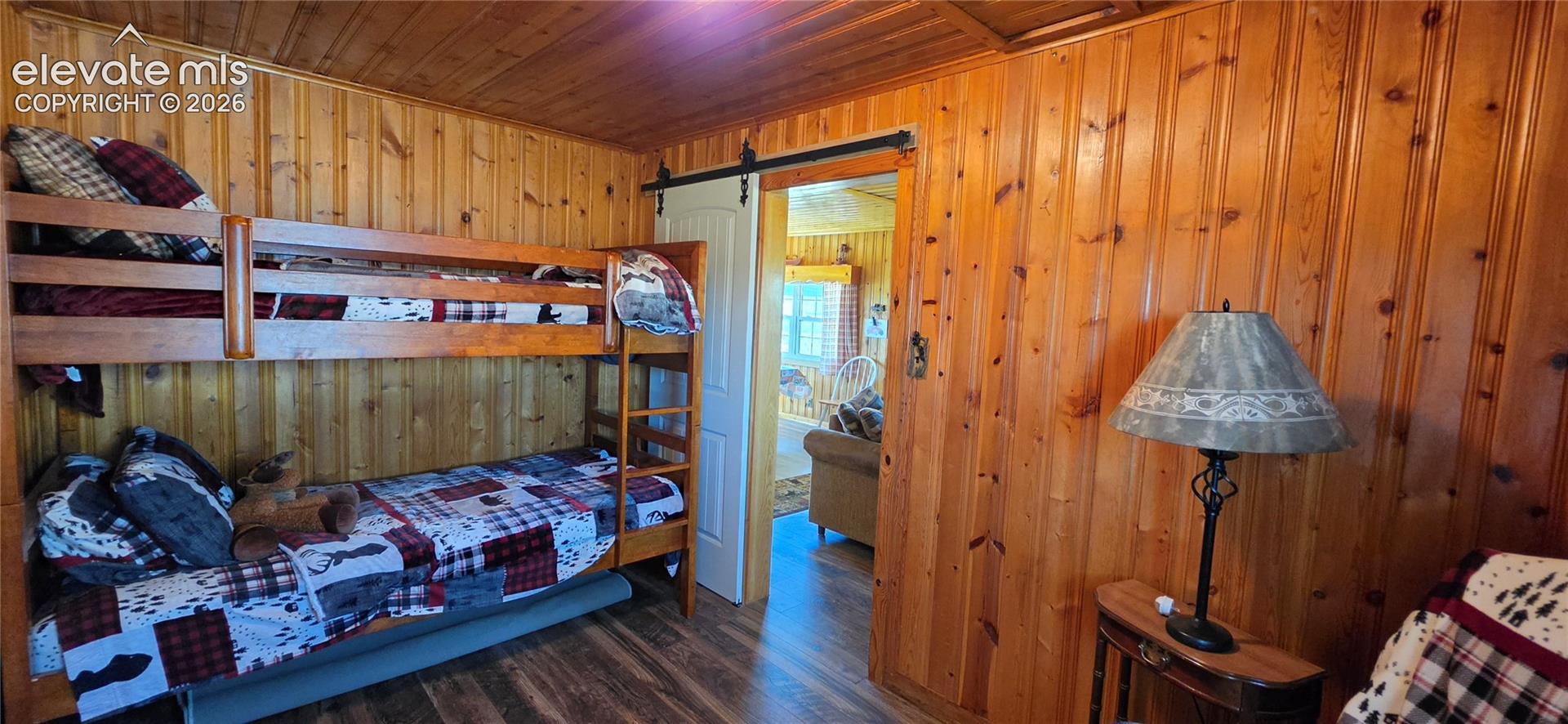 Wood-finish flooring, vertical wood plank wall and ceiling finishes, and a barn door entry