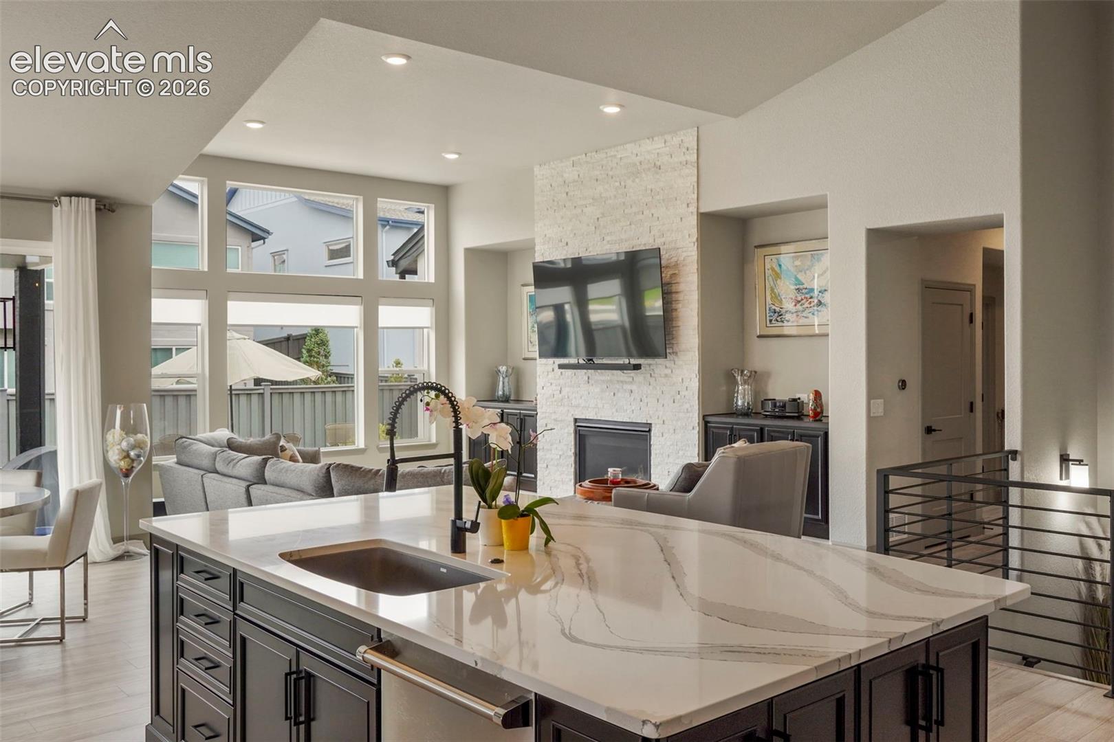 Kitchen island with a light-toned countertop, integrated sink, and dark wood-finish cabinetry