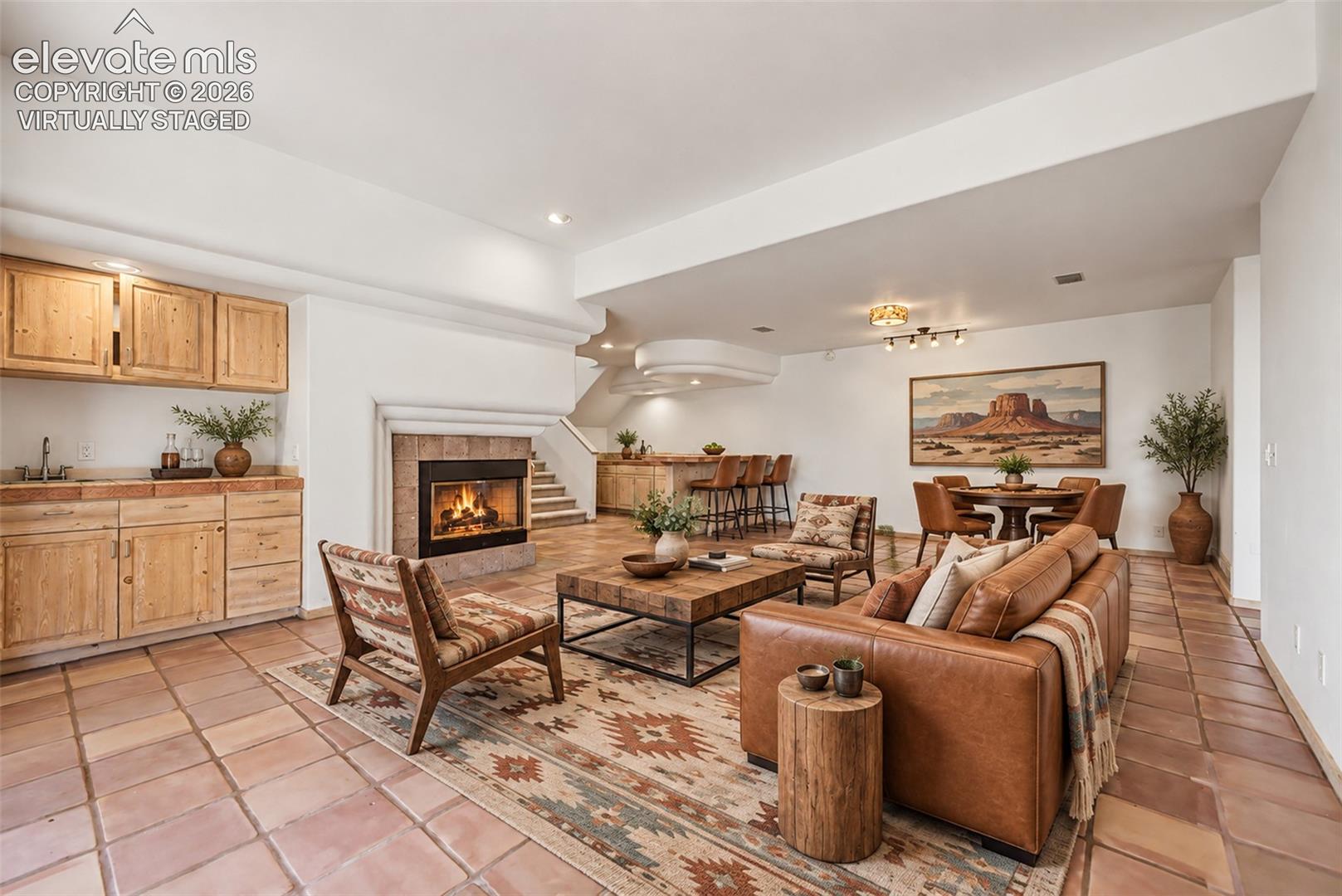 Virtually Staged
Terracotta tile flooring, stone-clad fireplace, integrated wet bar with wood cabinetry, built-in bar with seating, and staircase with wood treads