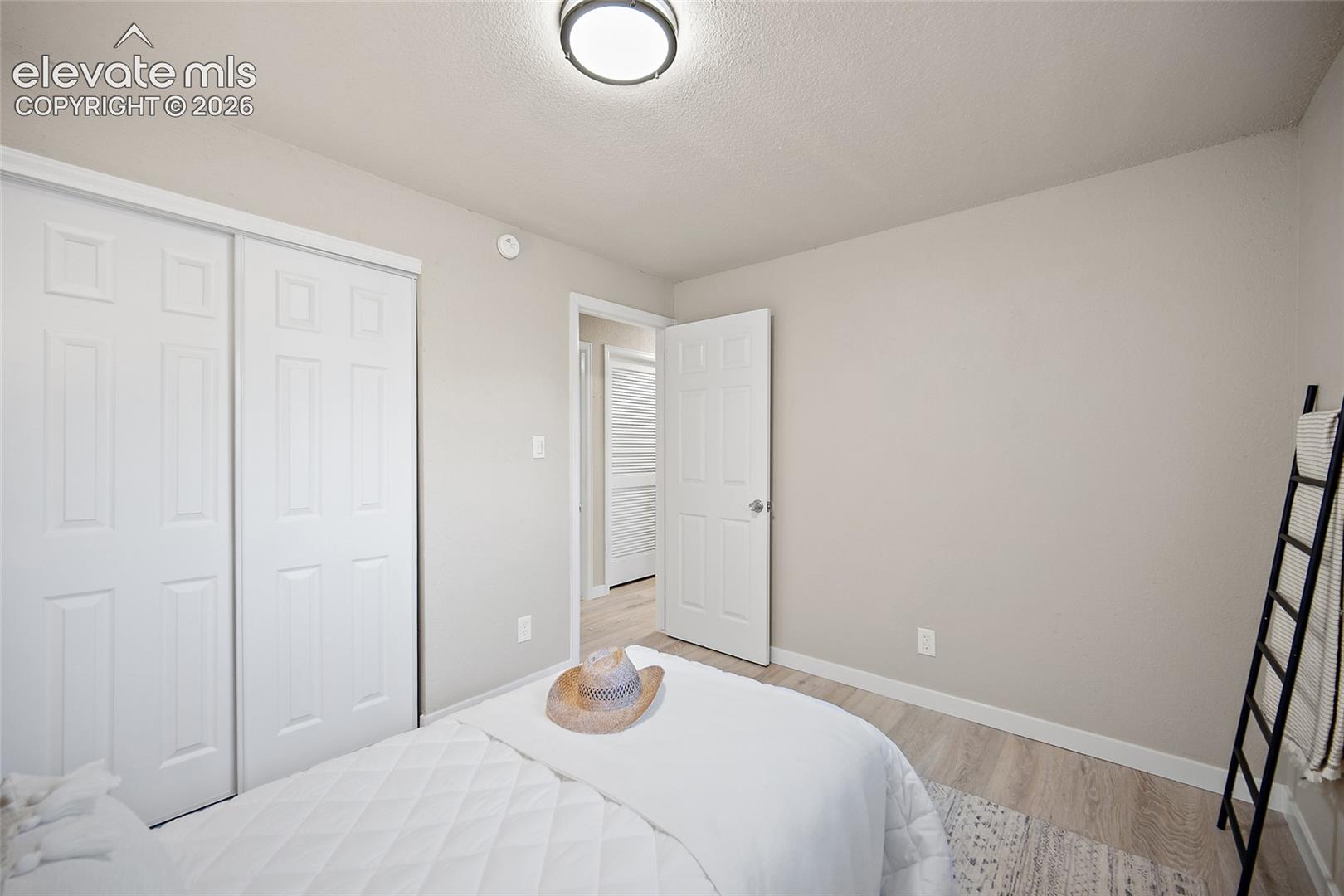 Light-toned wall paint with white trim, wood-finish flooring, and white bi-fold closet doors