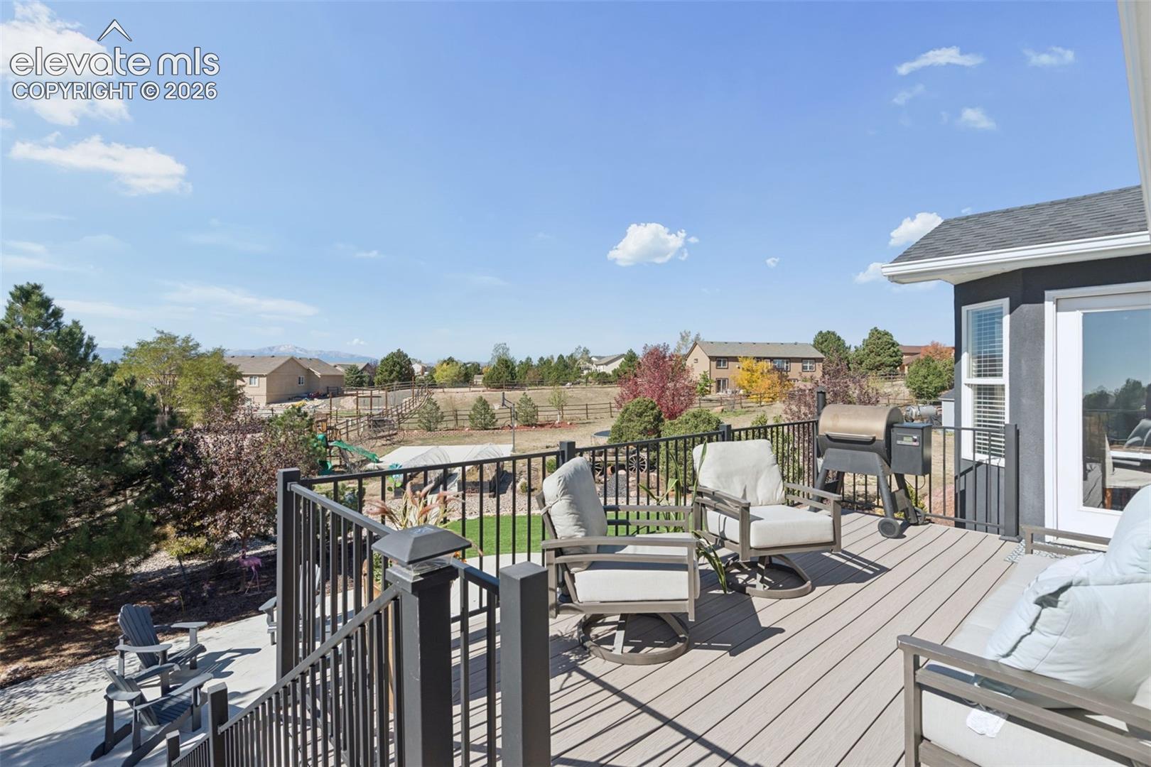 Expansive deck featuring composite decking, black metal railings, and a sliding glass door