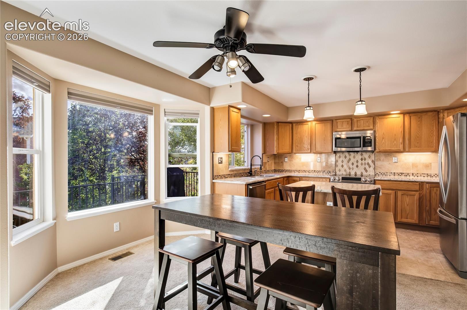 Enjoy casual meals at the breakfast bar or gather around the dining table, with generous windows overlooking the backyard + convenient access to the elevated composite deck.