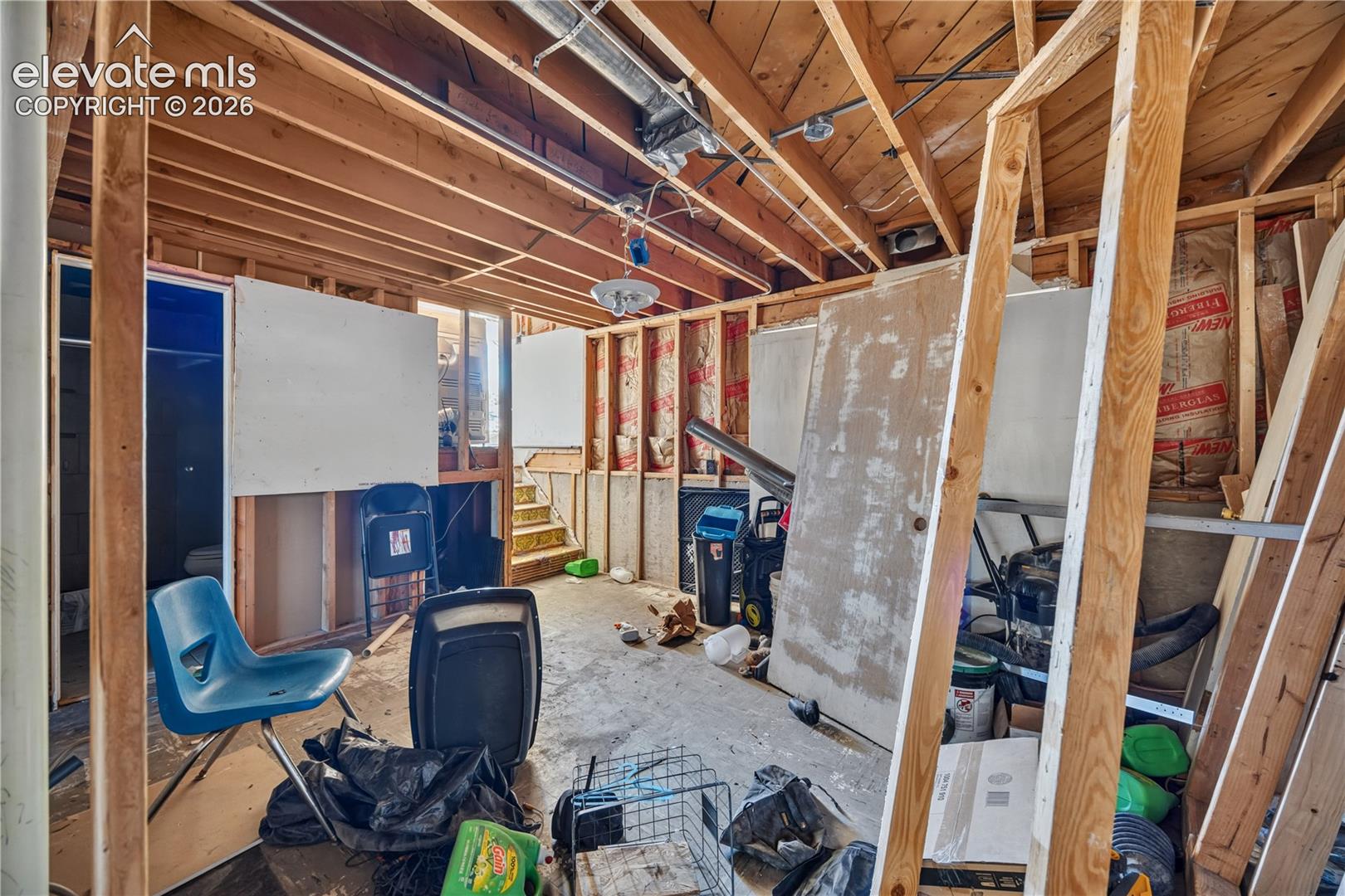 Unfinished interior space featuring exposed wood ceiling joists, concrete flooring, and open wood-frame wall construction with insulation