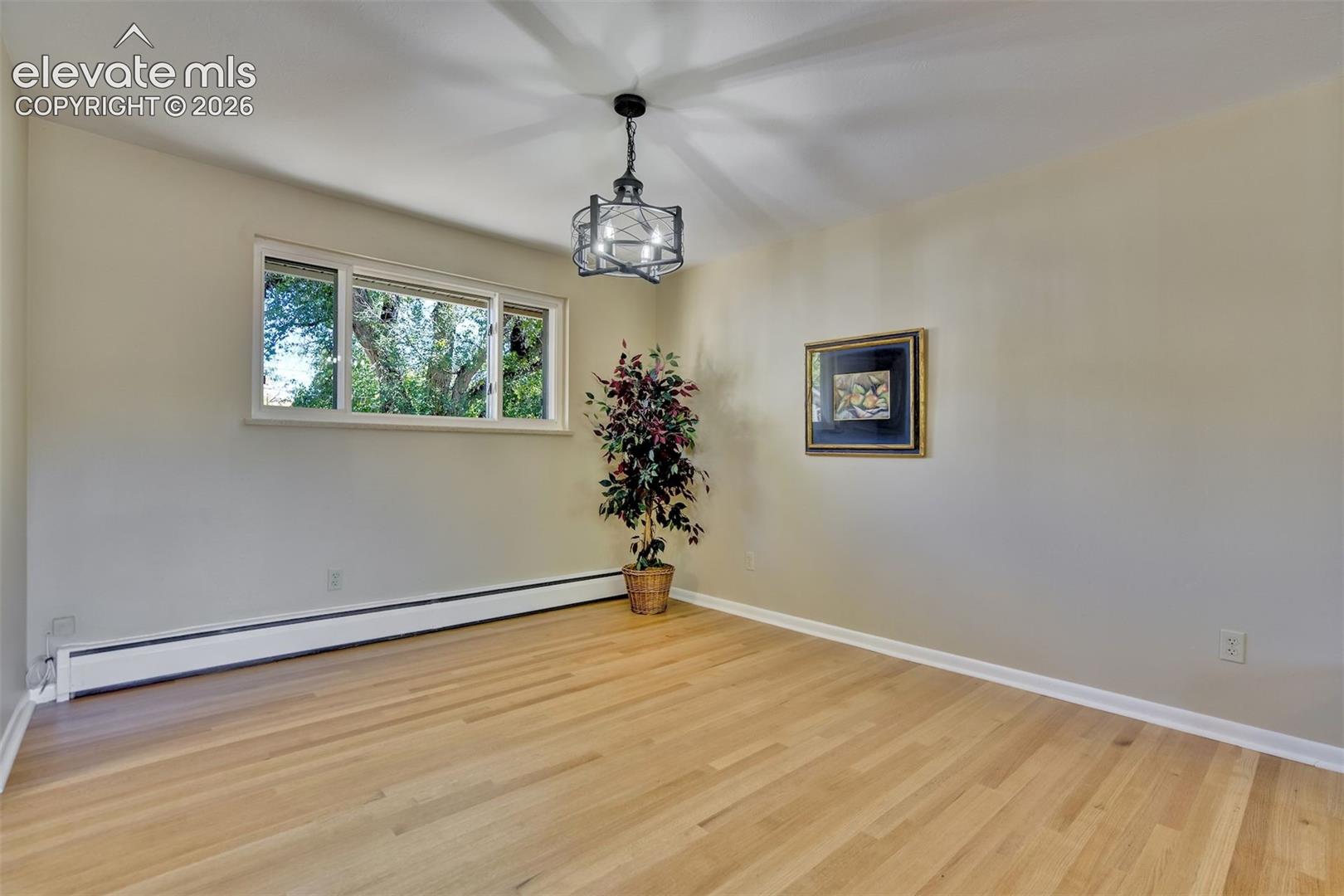 Room featuring wood-finish flooring, a metal cage-style chandelier, and a horizontal sliding window