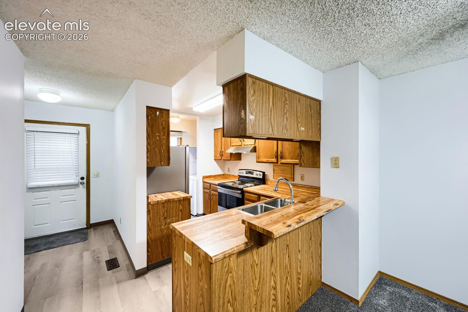 Kitchen featuring wood cabinetry, stainless steel sink, and wood-finish countertops