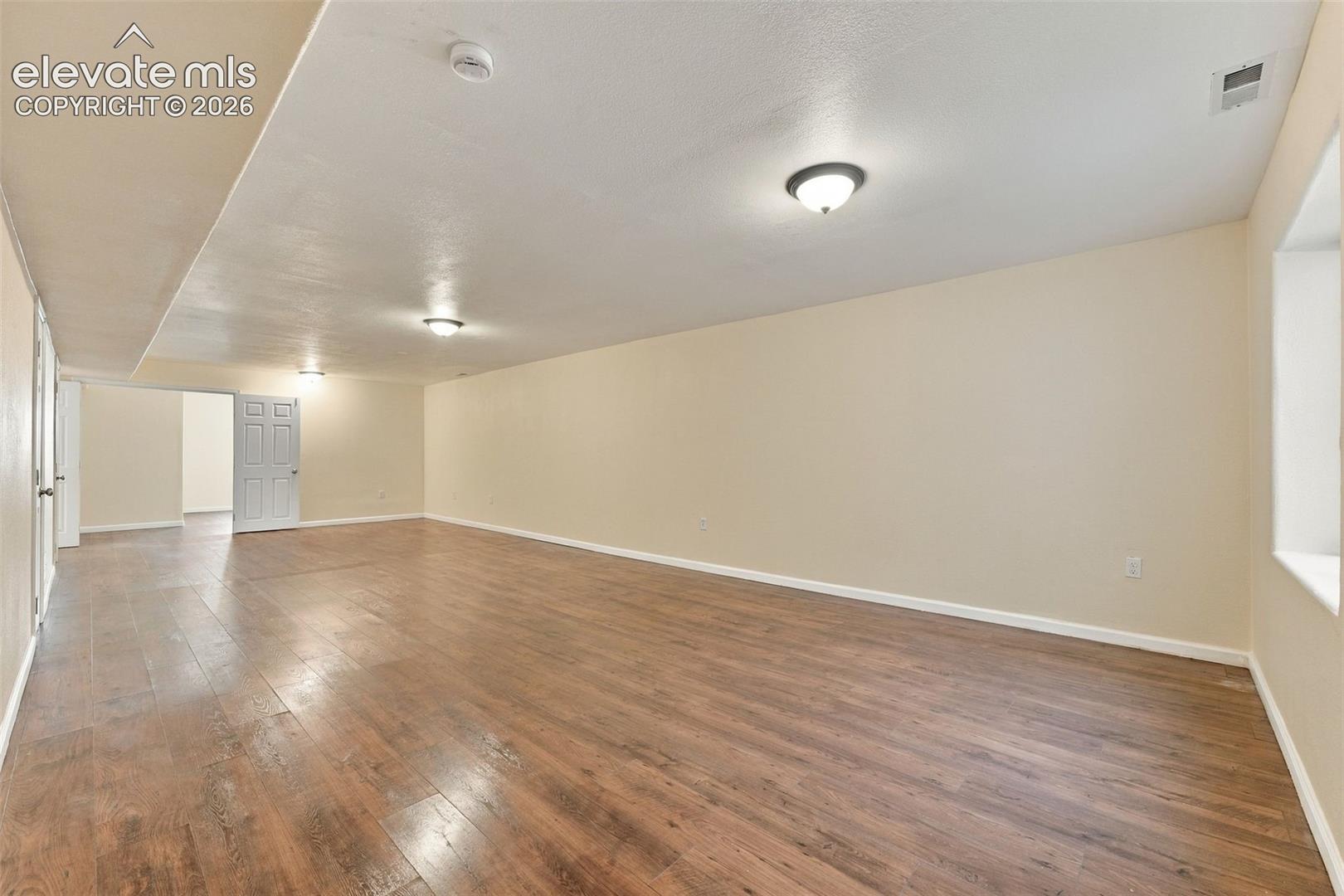 Spacious interior featuring wood-finish flooring, neutral wall paint, and multiple flush-mount ceiling lights