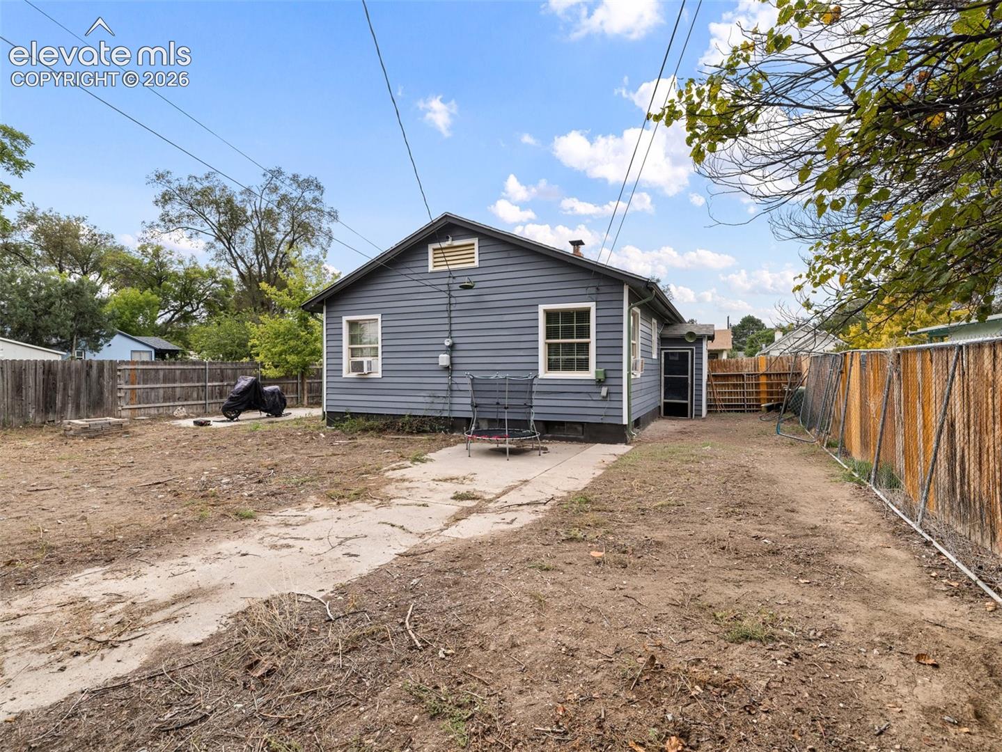 Rear exterior featuring siding, white trim windows, and fenced perimeter