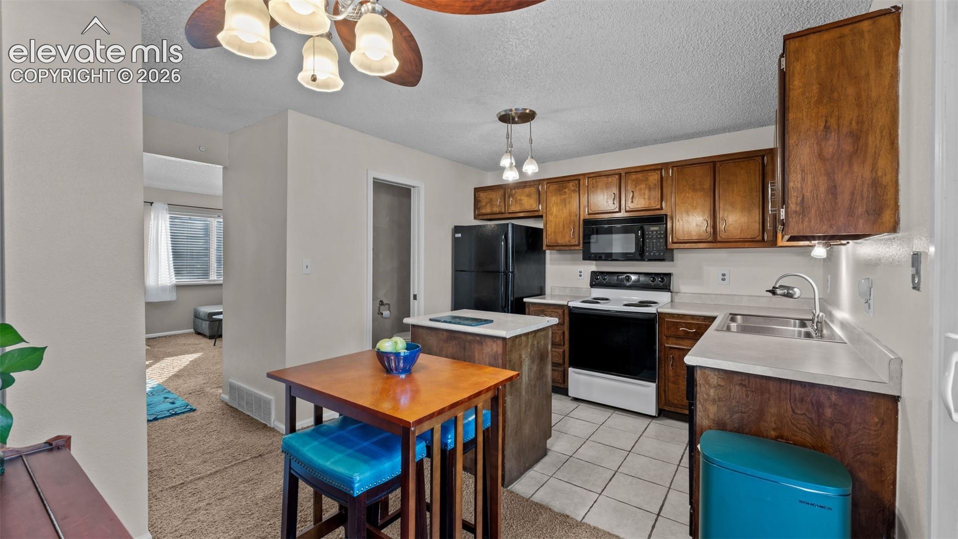 Kitchen featuring wood cabinetry, a central island, solid-surface countertops, tile flooring, and integrated lighting fixtures