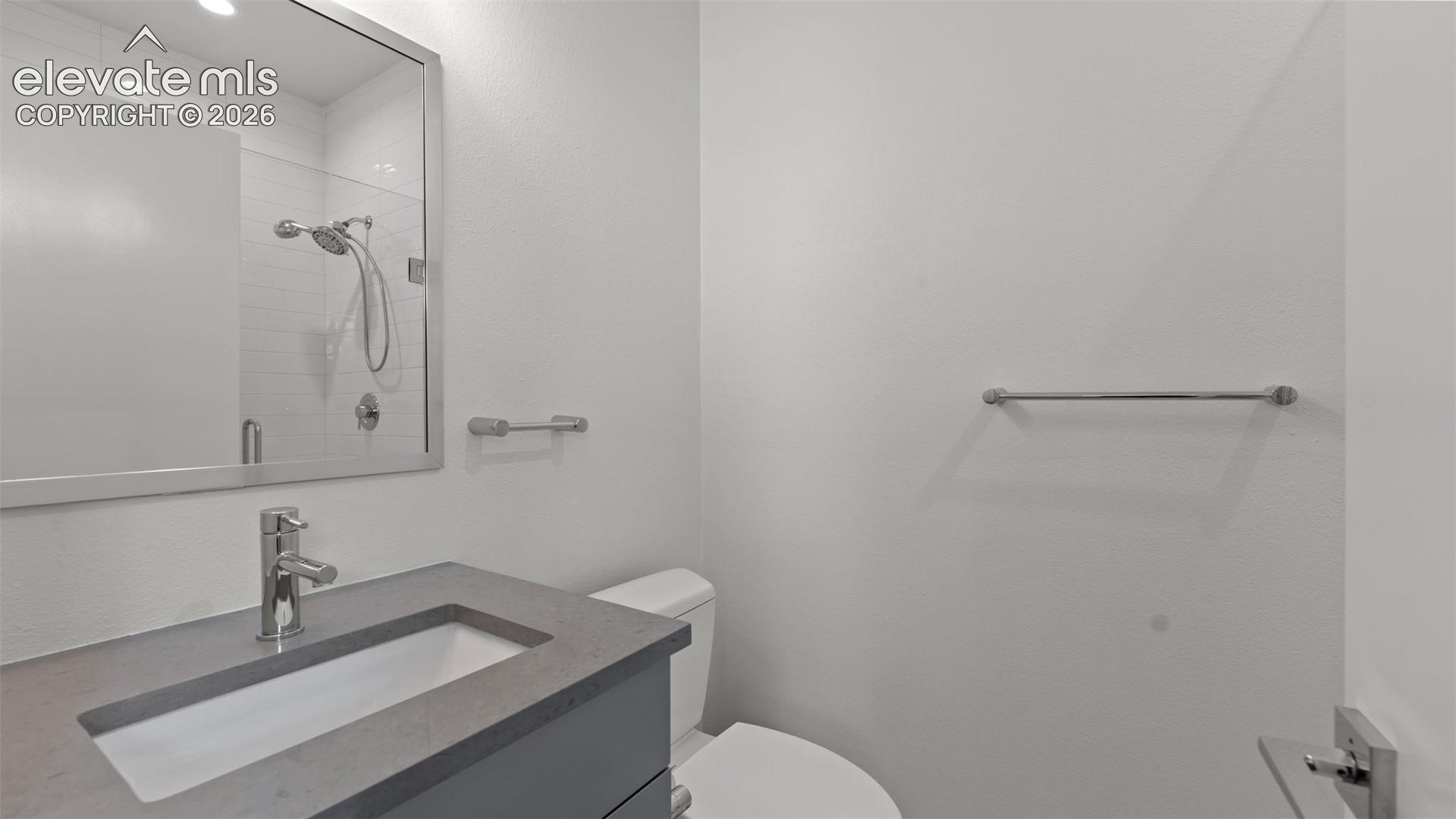 Modern vanity featuring a grey countertop, integrated rectangular sink, chrome fixtures, framed mirror, and chrome towel hardware