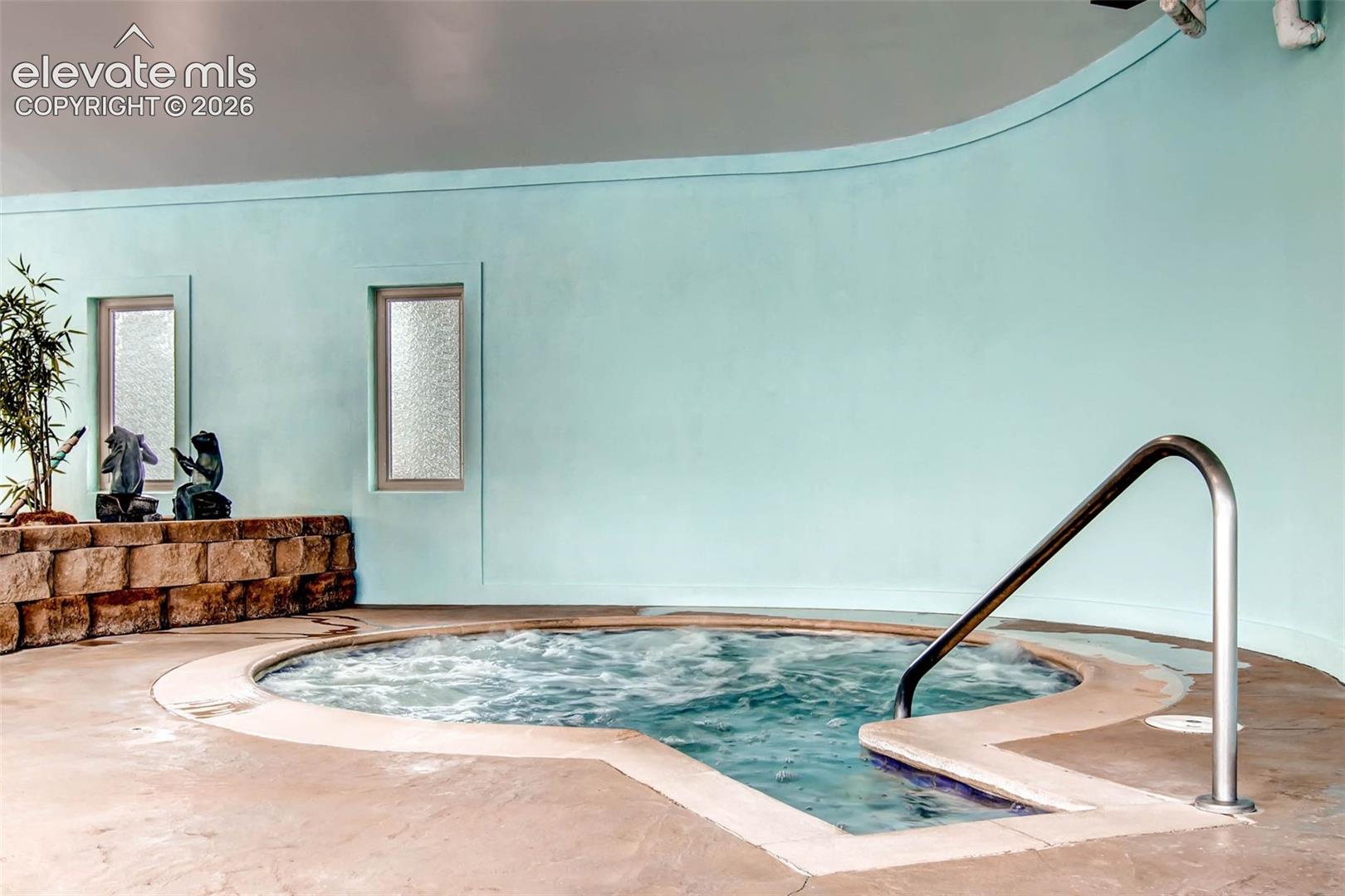 Built-in spa with polished handrail, surrounded by textured concrete decking